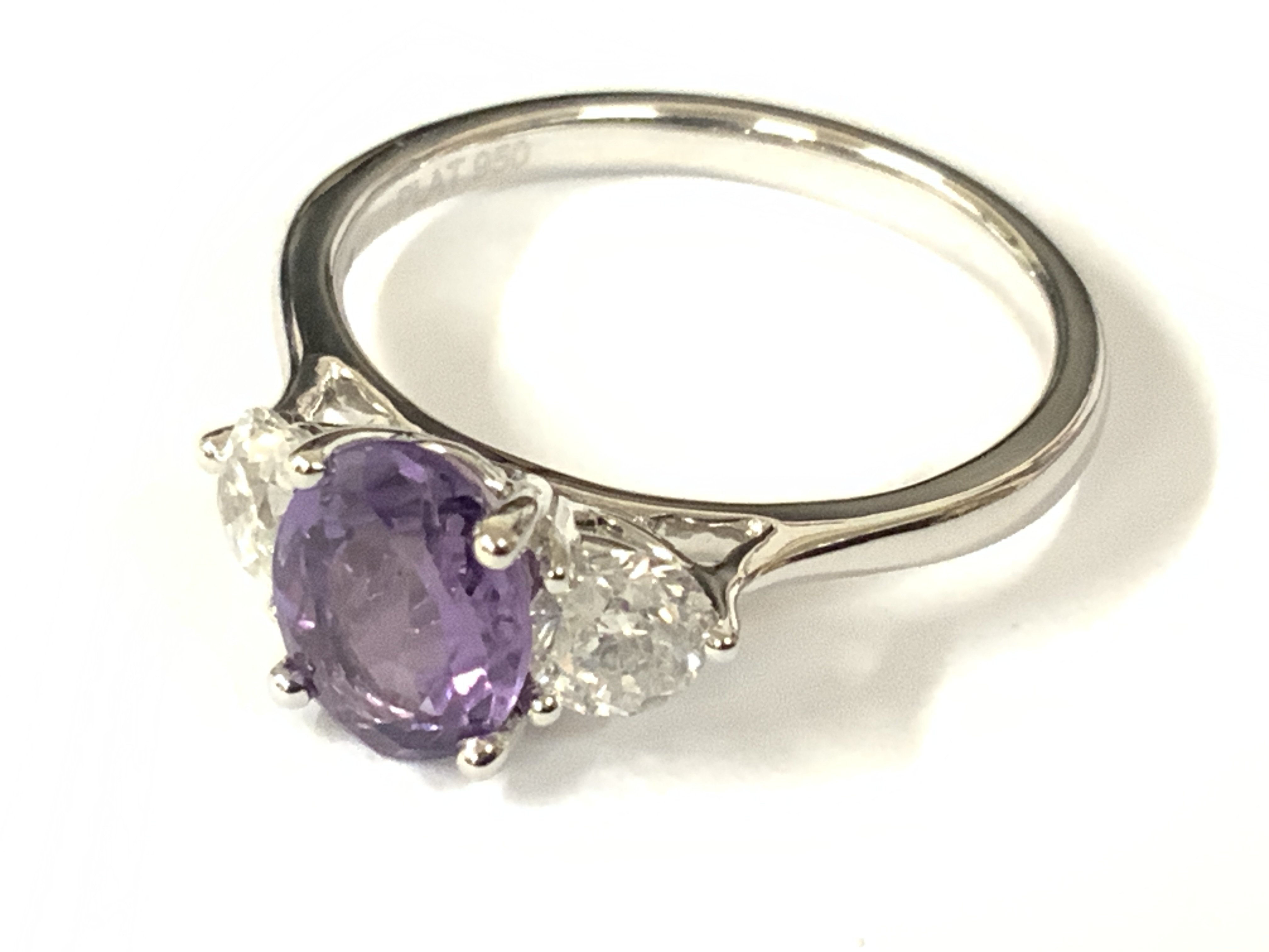 Platinum trilogy ring set with a round purple sapphire flanked by RBC diamonds. Sapphire 1.30ct. Diamonds 0.57ct. Approx ring size L. postage category A.