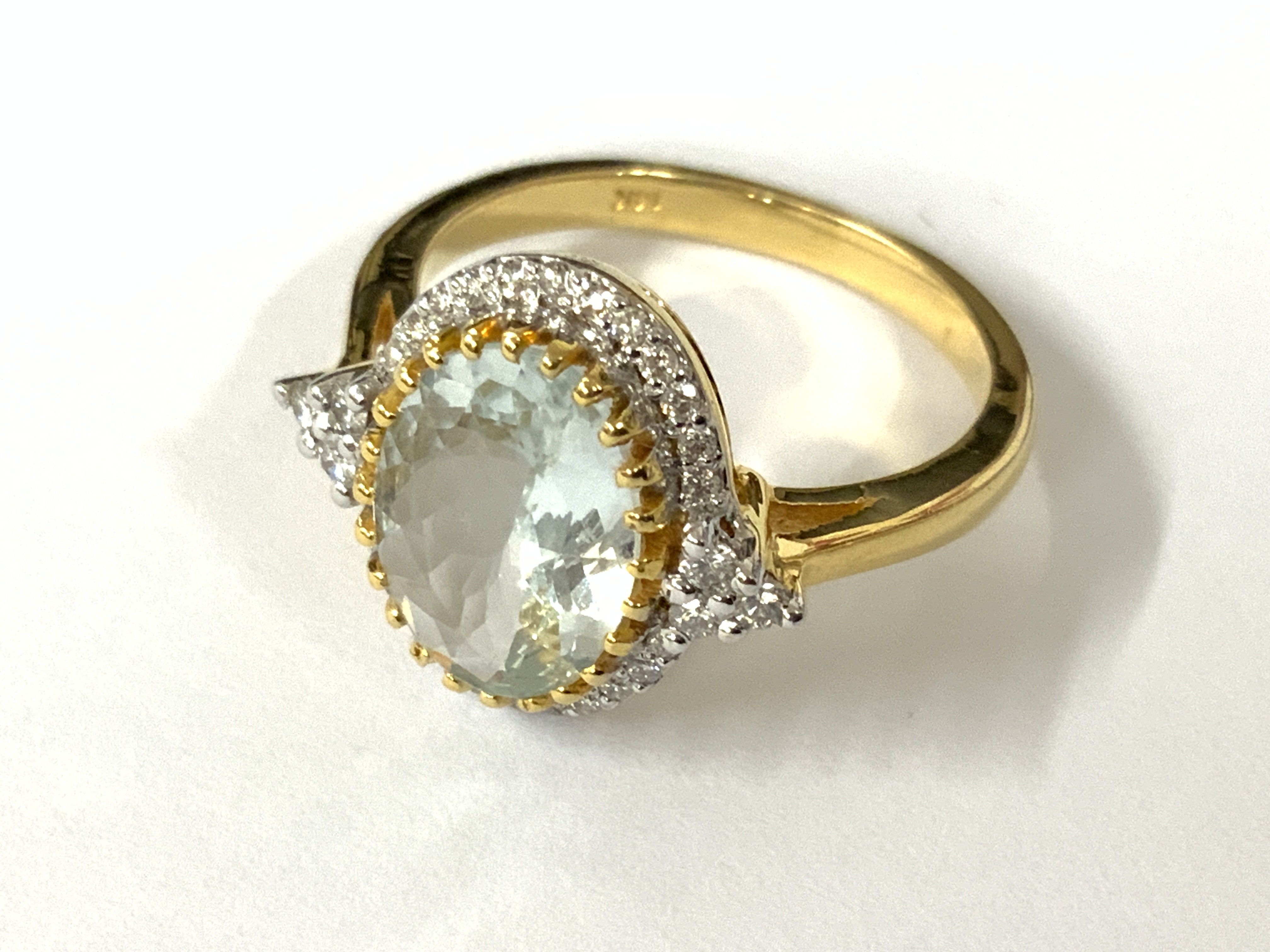14ct yellow gold oval aquamarine and RBC and R/C diamond set cluster with diamonds to the shoulders. Aquamarine 2.01ct. Diamonds 0.23ct. Approx ring size O/P. Postage category A