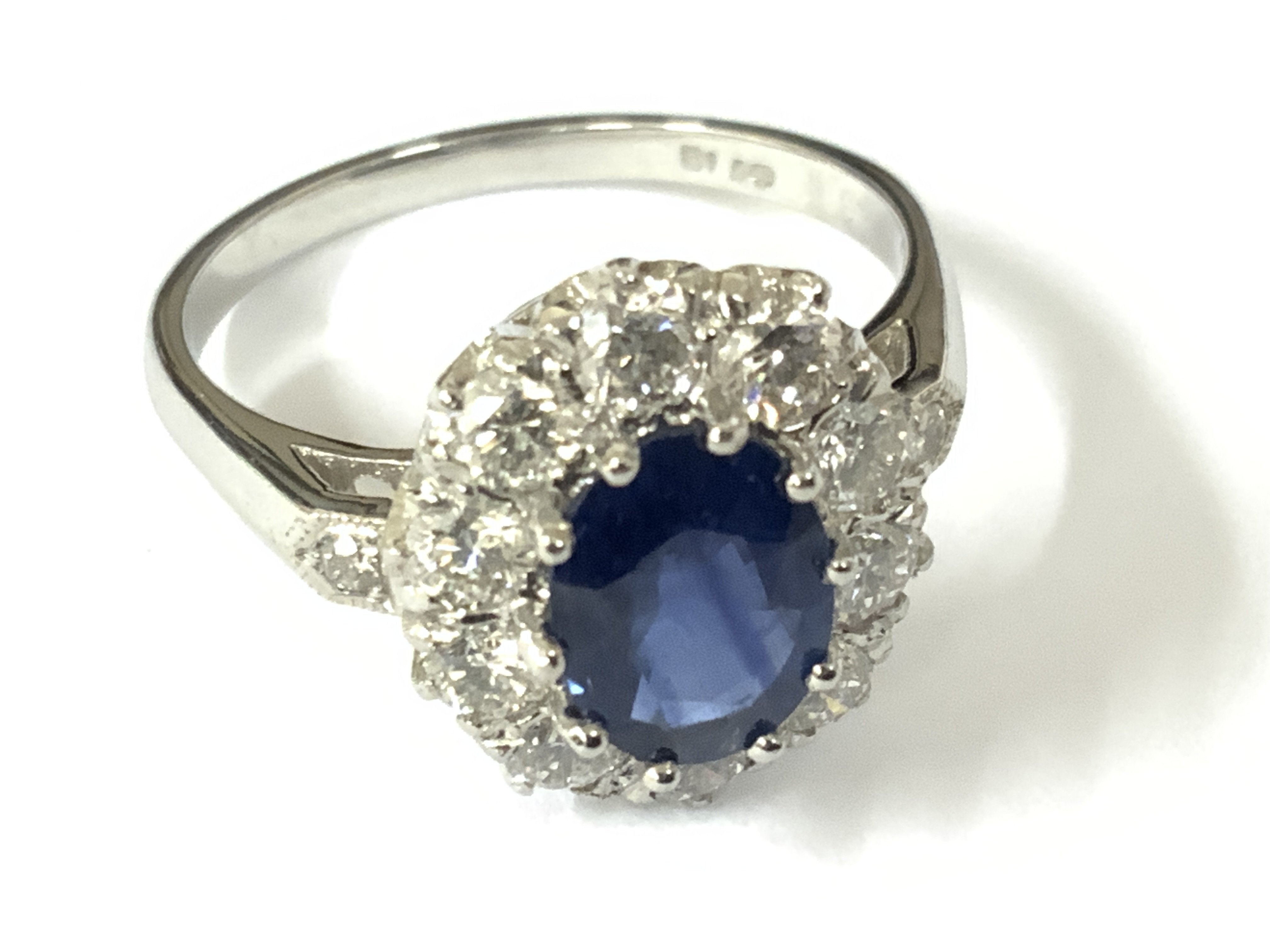 Platinum ring set with an oval sapphire, halo of RBC diamonds and diamond set shoulders. Sapphire 1.50ct approx. Diamonds 0.85ct approx. Approx ring size N. Postage category A