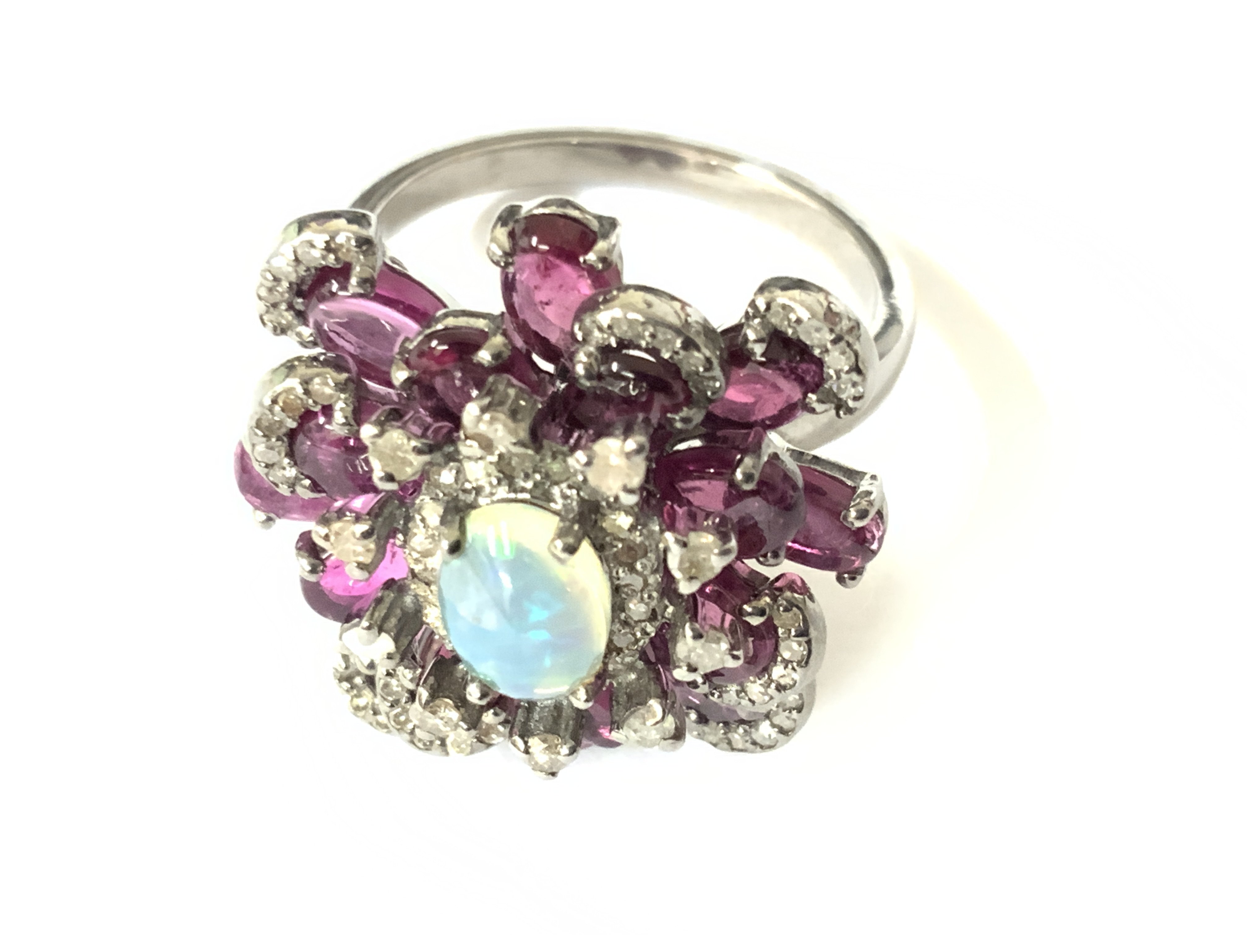 Elaborate silver ring set with an oval cabochon opal, pink tourmalines and diamonds with vintage style box. Opal 0.50ct. Tourmalines 2.65ct approx. Diamonds 0.40ct. Approx ring size N/O. Postage category A