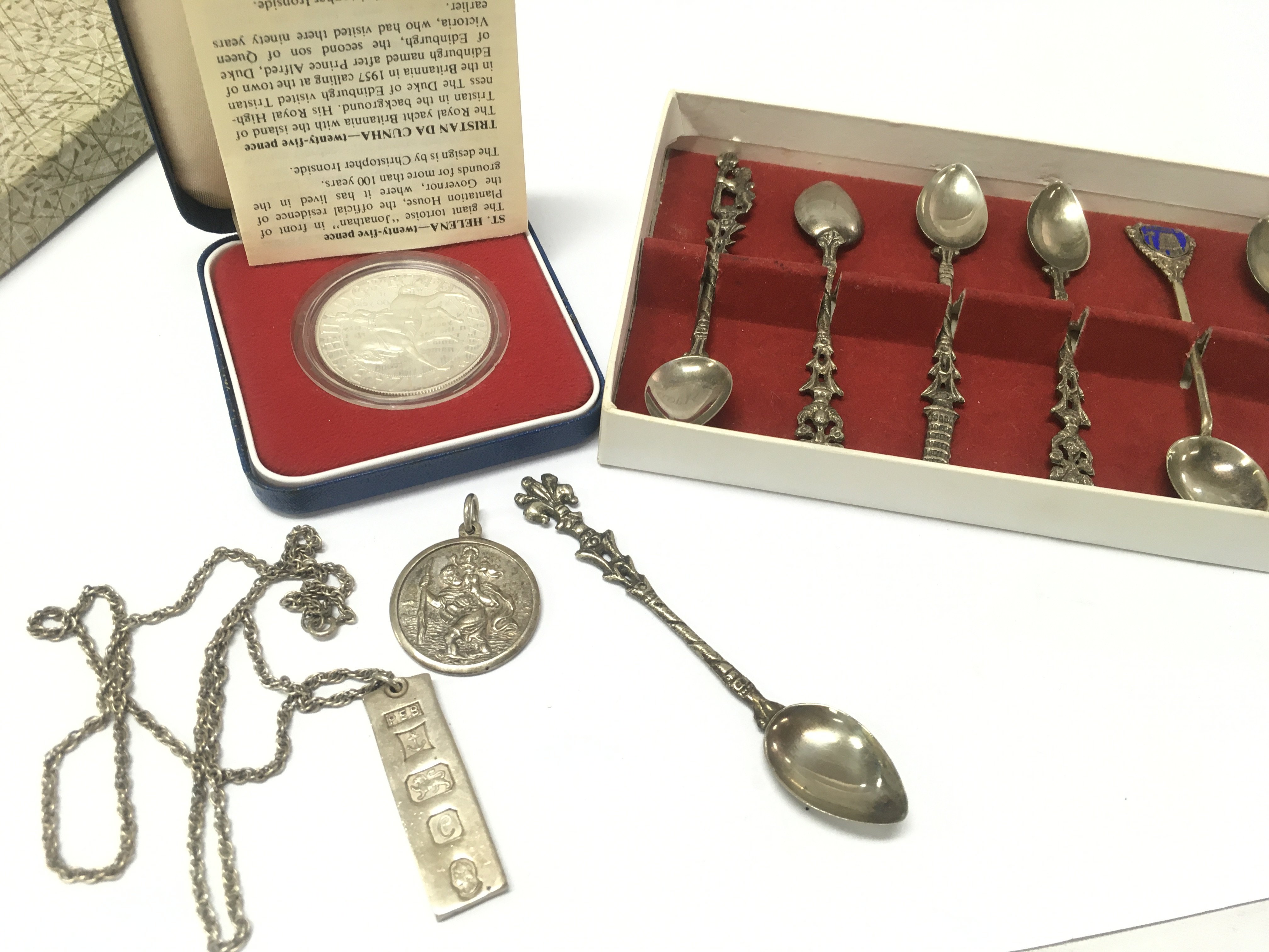 A silver ingot necklace pendant , 1977 sterling silver proof crown , silver st Christopher pendant and cased spoons . Postage category B