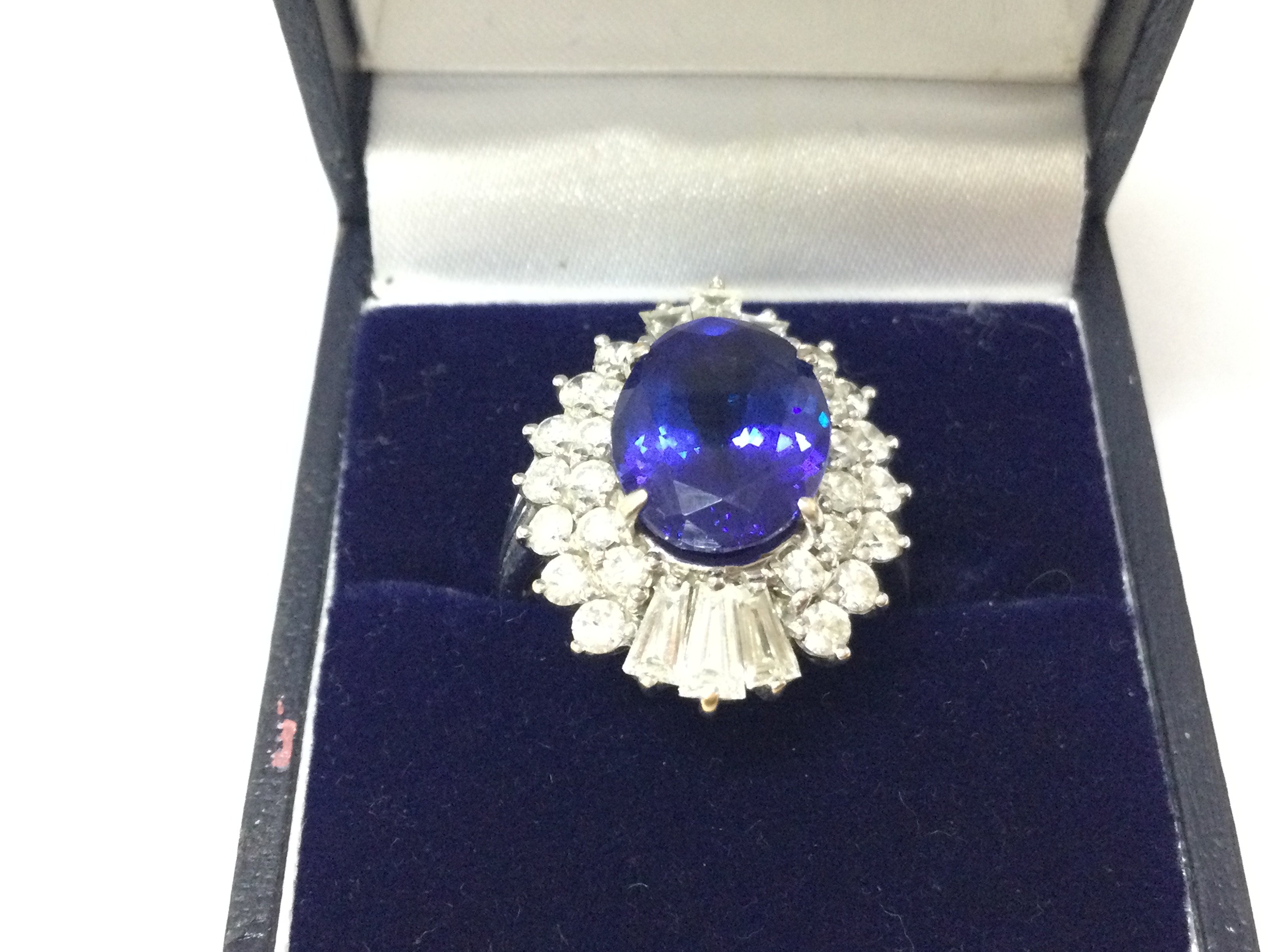 A white gold large oval Tanzanite and diamond ring. Tanzanite carat weight 4.50ct set with 26 round diamonds and 6 tapper baguettes weighing 1.10ct Size N with gemologists report
