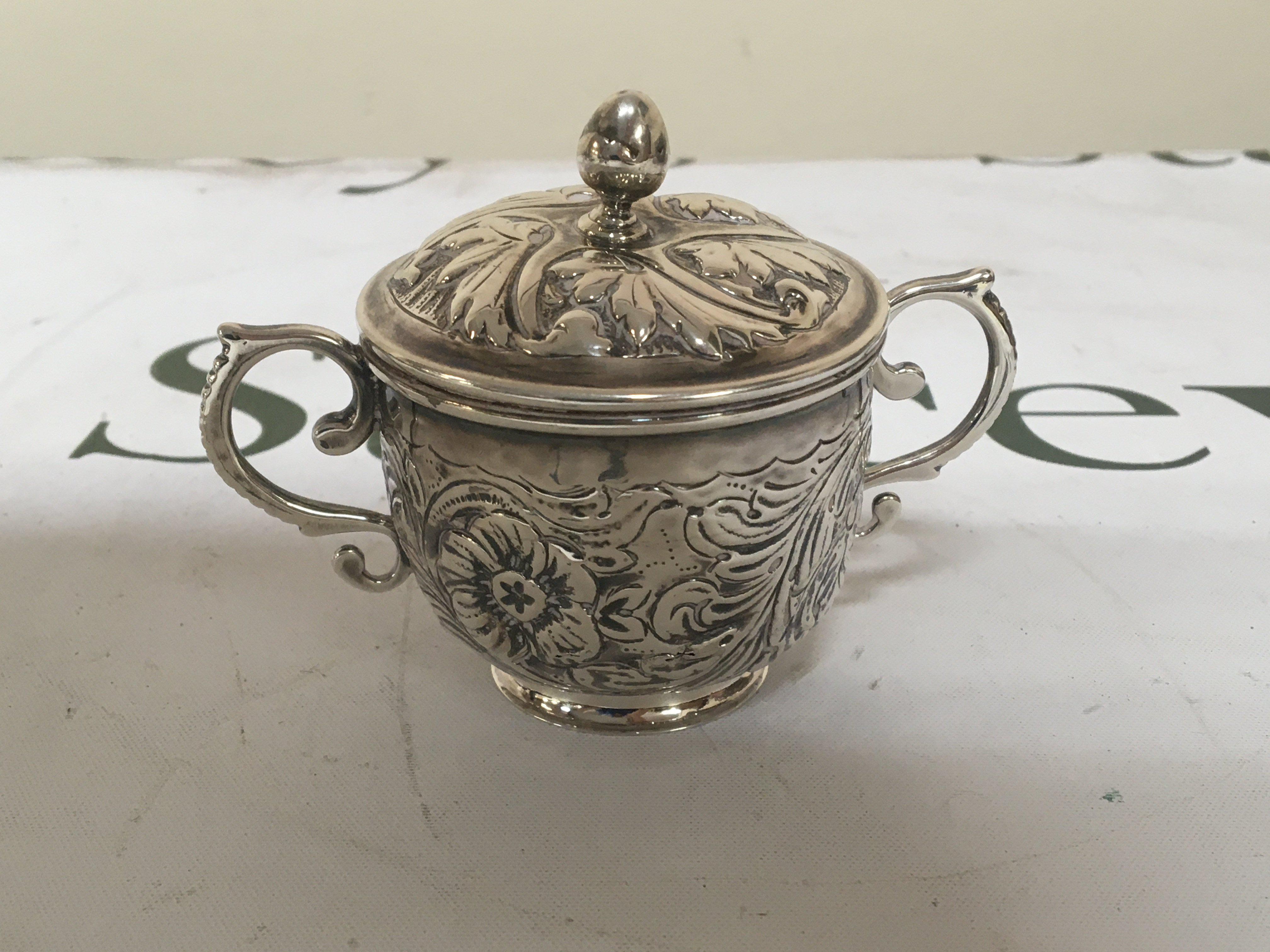 A small silver Porringer and cover with scroll handles repousse chased marks the base height 7cm weight 108g