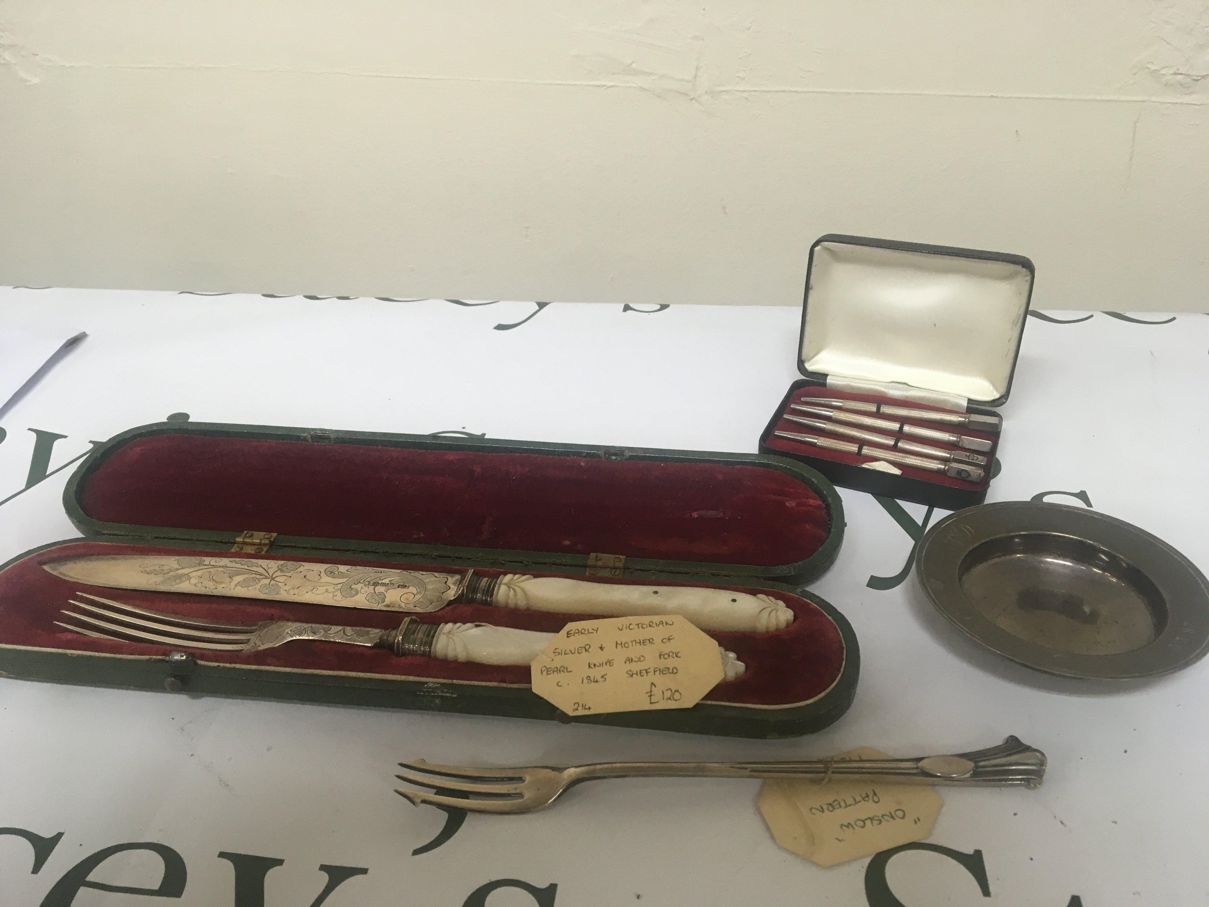 A Quality cased Victorian silver knife and folk with mother of pearl handles Sheffield hallmarks a pickle fork cased set of silver bridge pencils and a small silver dish. (4)