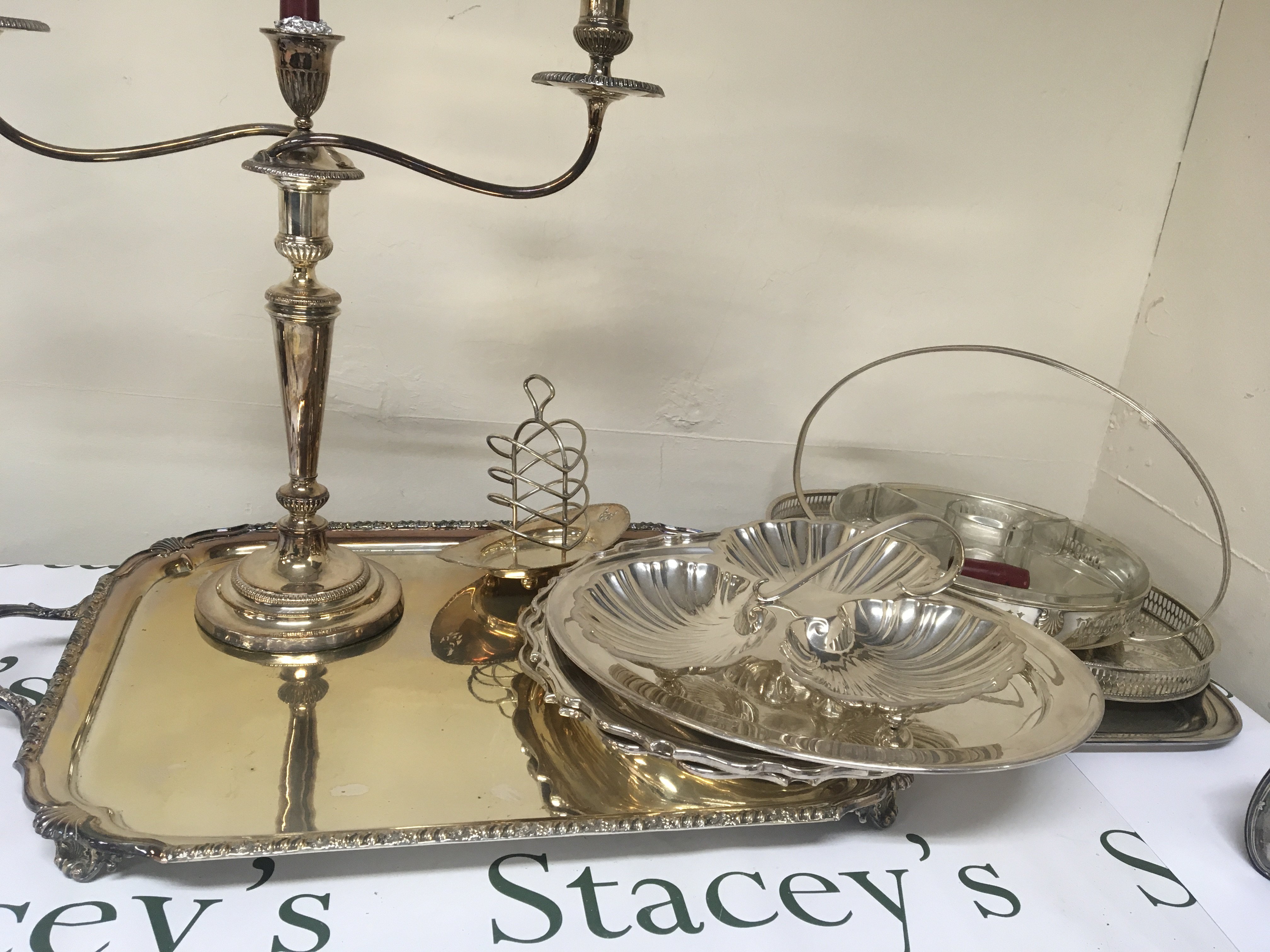 A large silver plated tray other silver plated serving dishes a candelabra orderve dish and other plate.