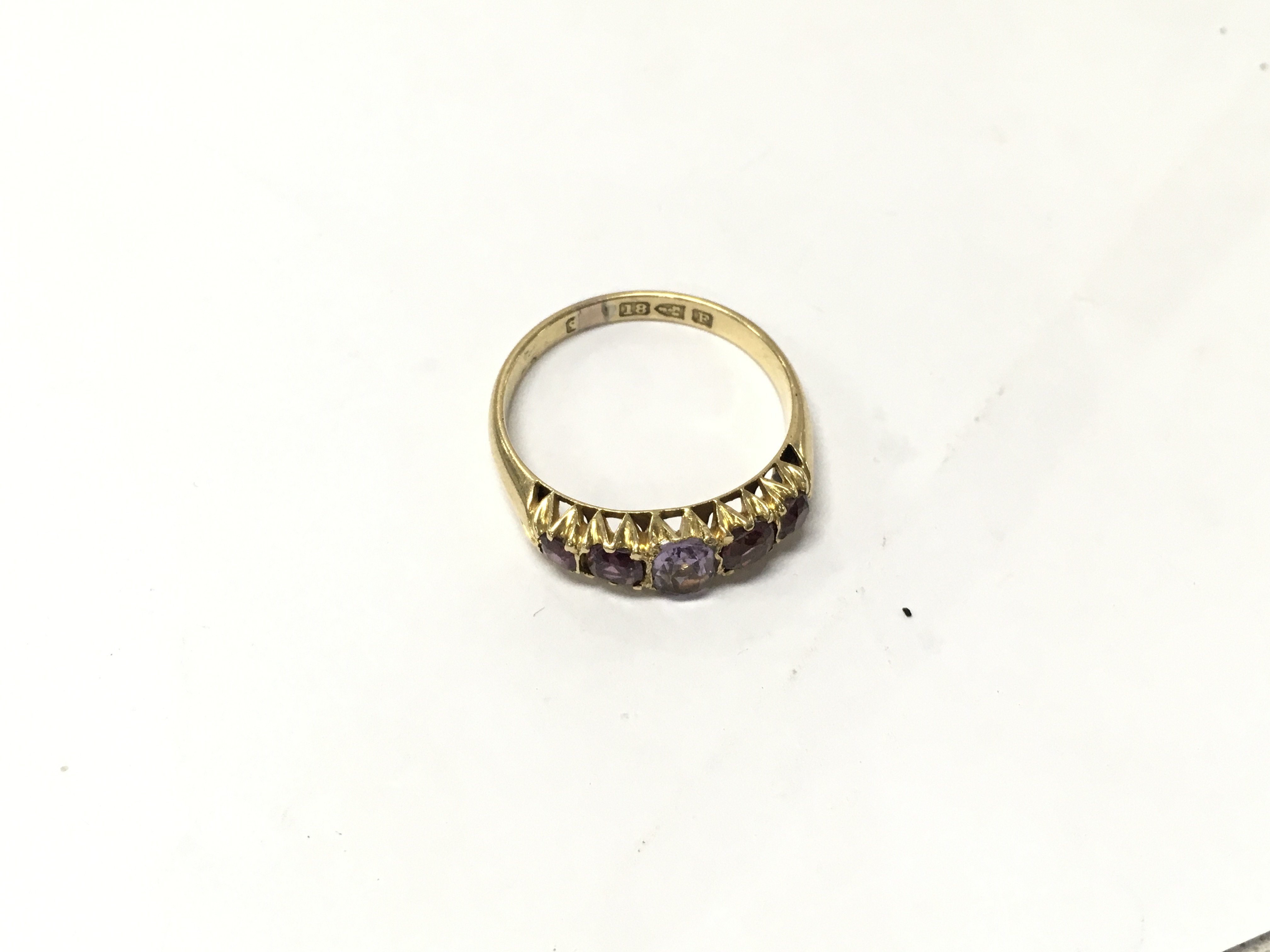 An 18ct gold five stone purple ring. Size O1/2, Approx weight 2.5grams.