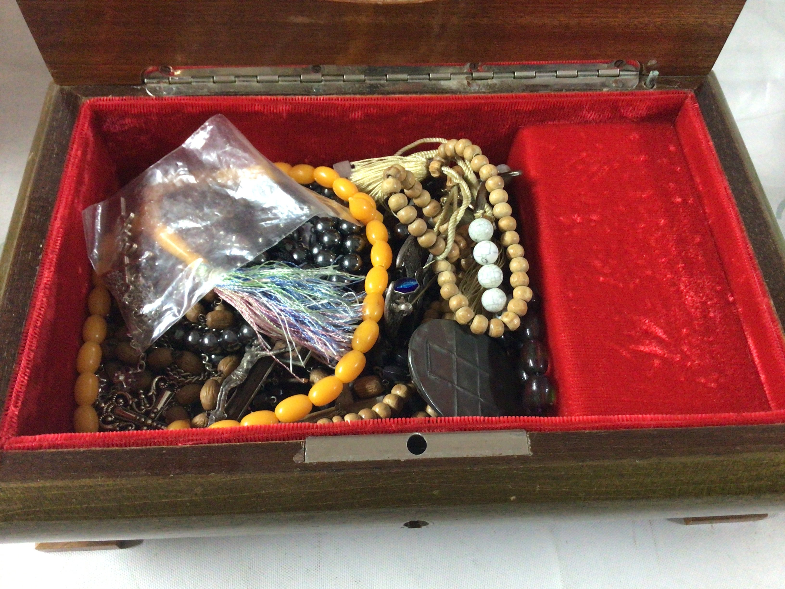 A wooden jewellery box containing cross pendants, rosaries and prayer beads.