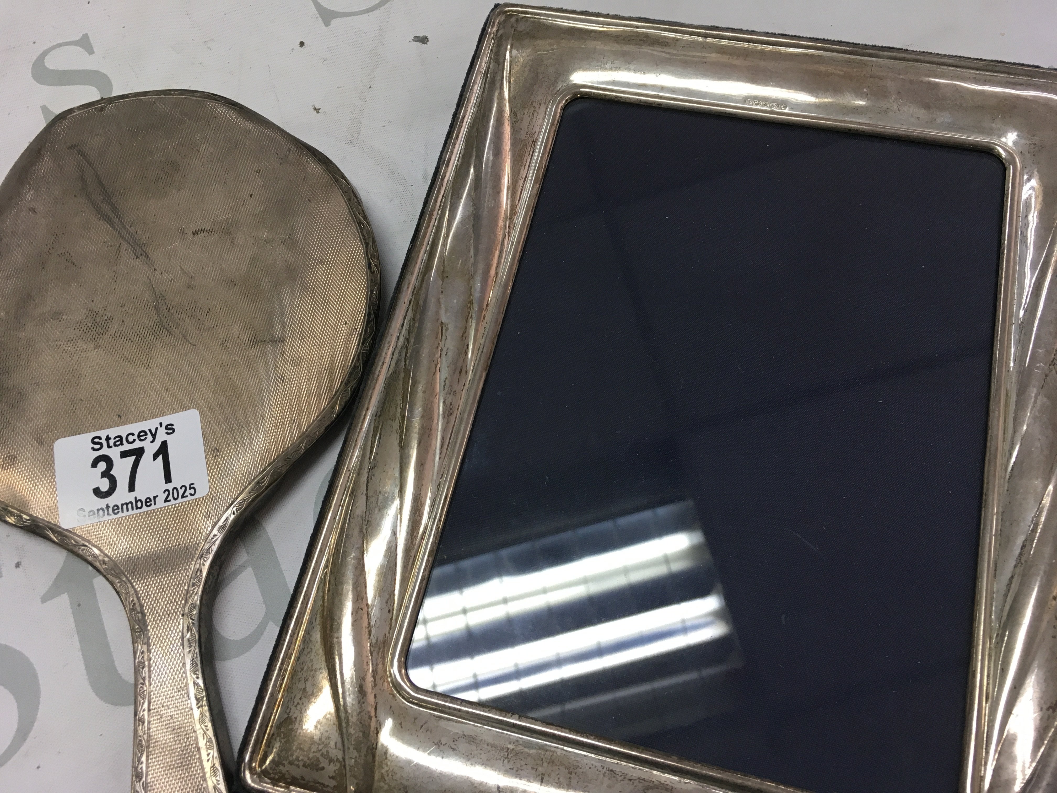 A silver hand mirror and a silver photo frame.
