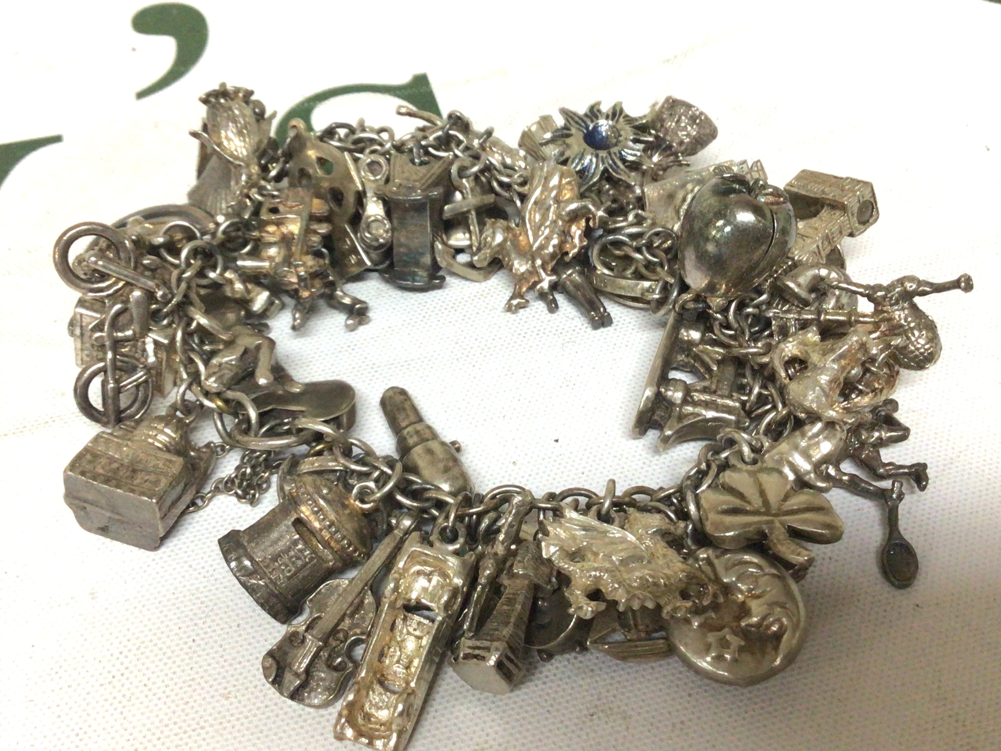 A silver charm bracelet with numerous charms. Weight 137g approximately.