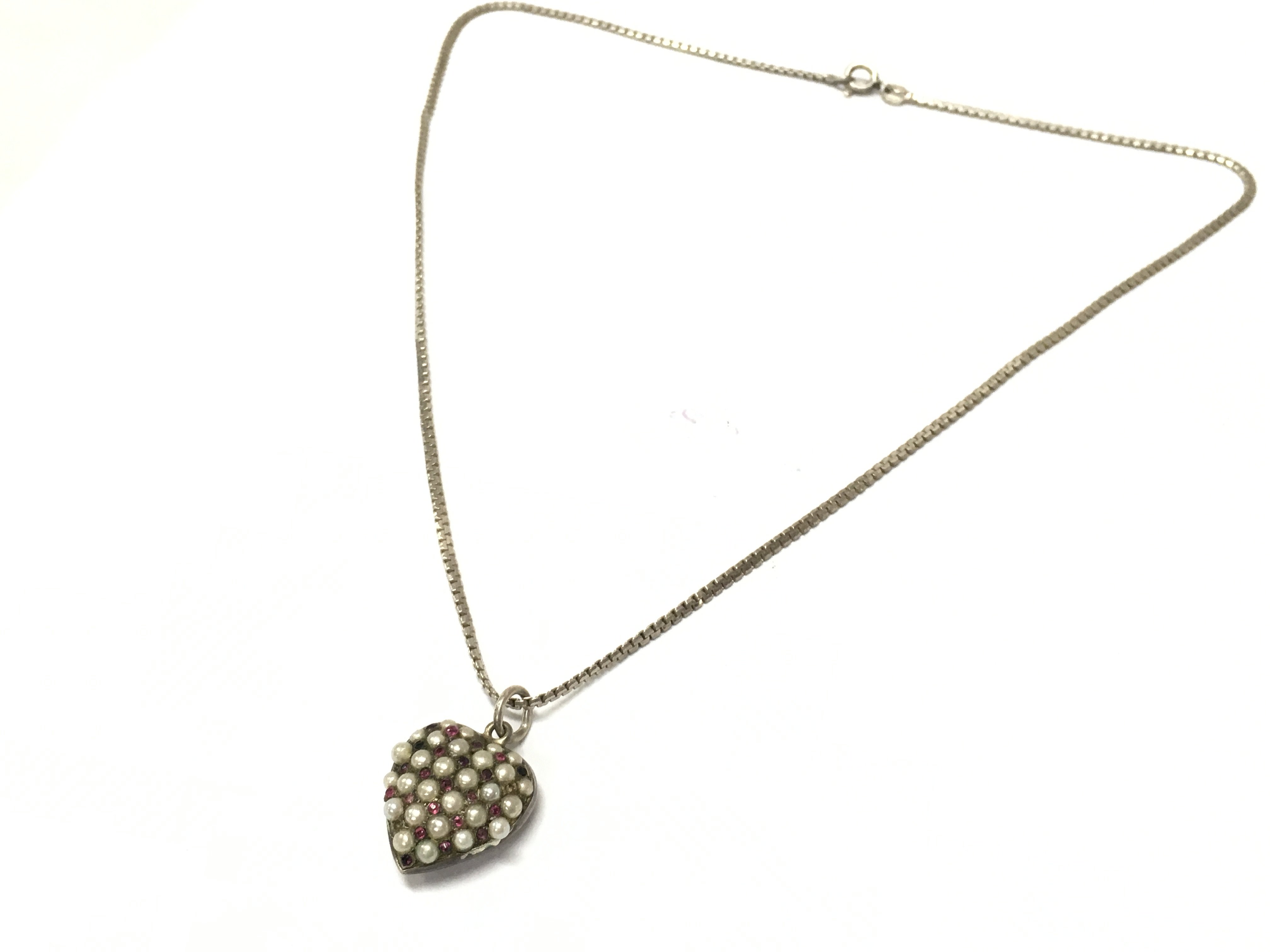 An antique heart pendant set with pearls and coloured stones on a silver chain , postage catA