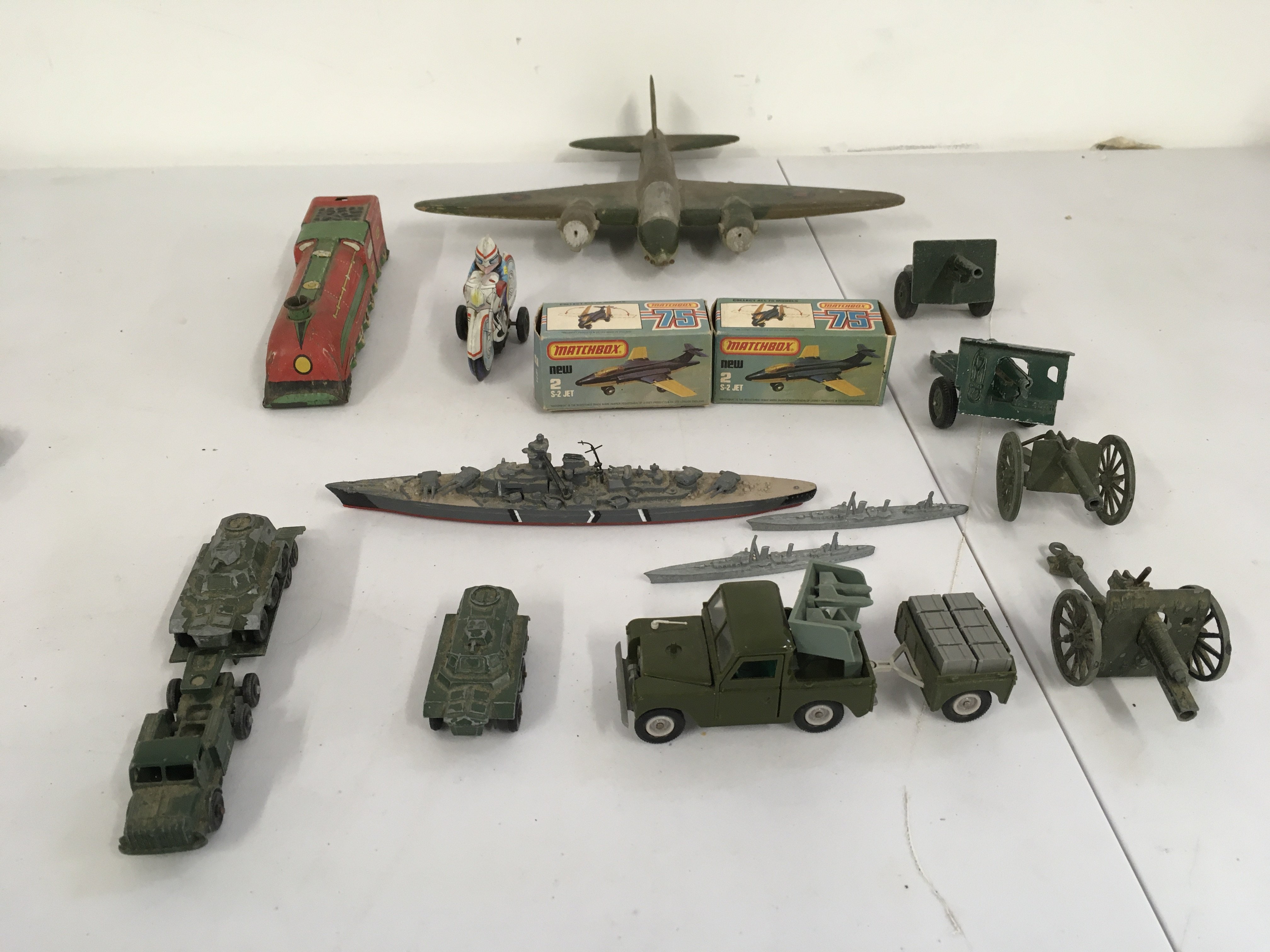 An assorted group featuring 2 boxed matchbox 75 S2 jets a tinplate train and police motrcycle. Various military themed items including ships, cars and a wooden hand made plane. No reserve