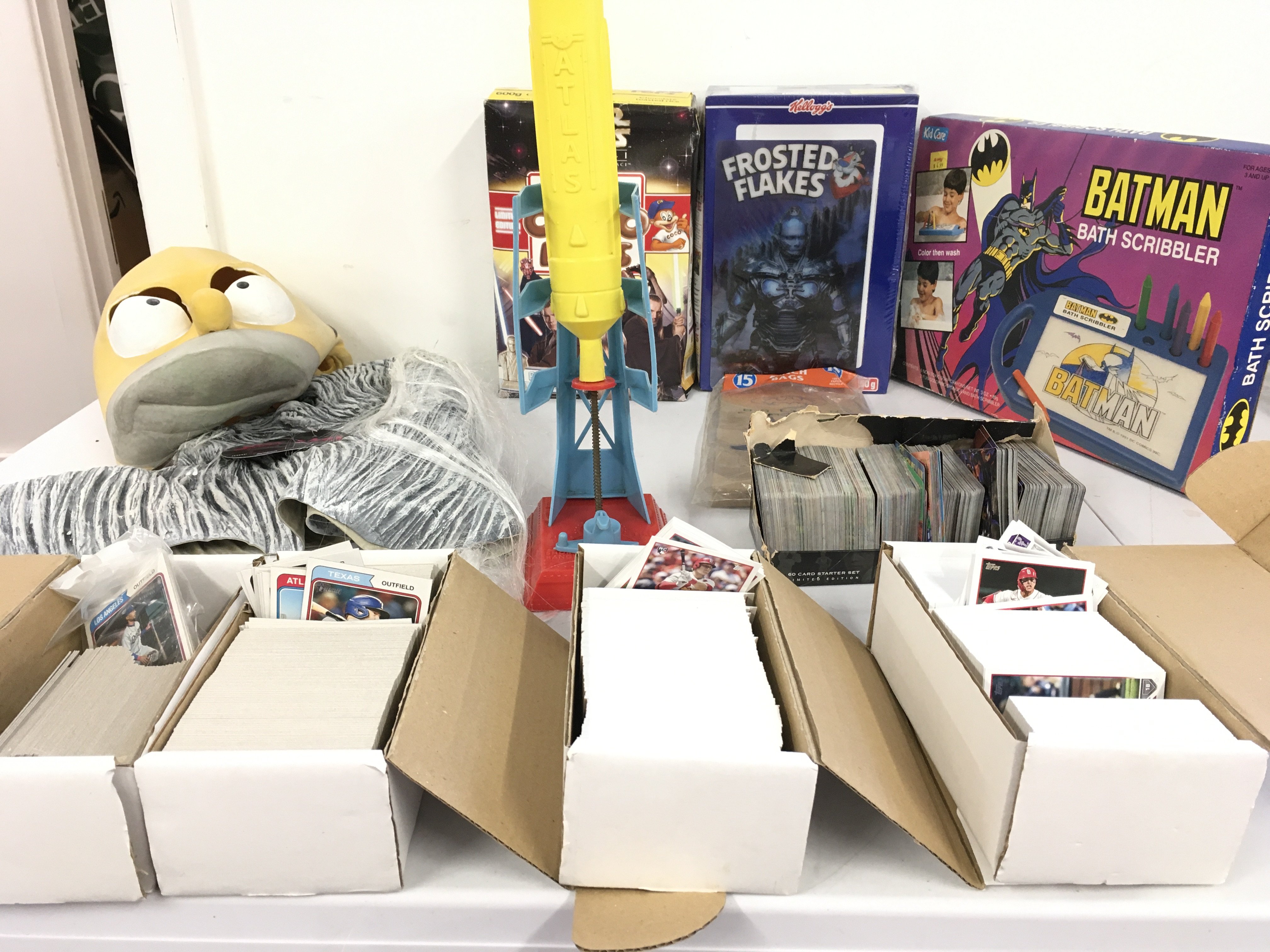 A varied lot comprising gaming and baseball cards..a pair of rubber masks&hellip;Batman items &hellip;atlas rocket launcher and two unopened boxes of cereals with free gifts the use by date has expired . No reserve