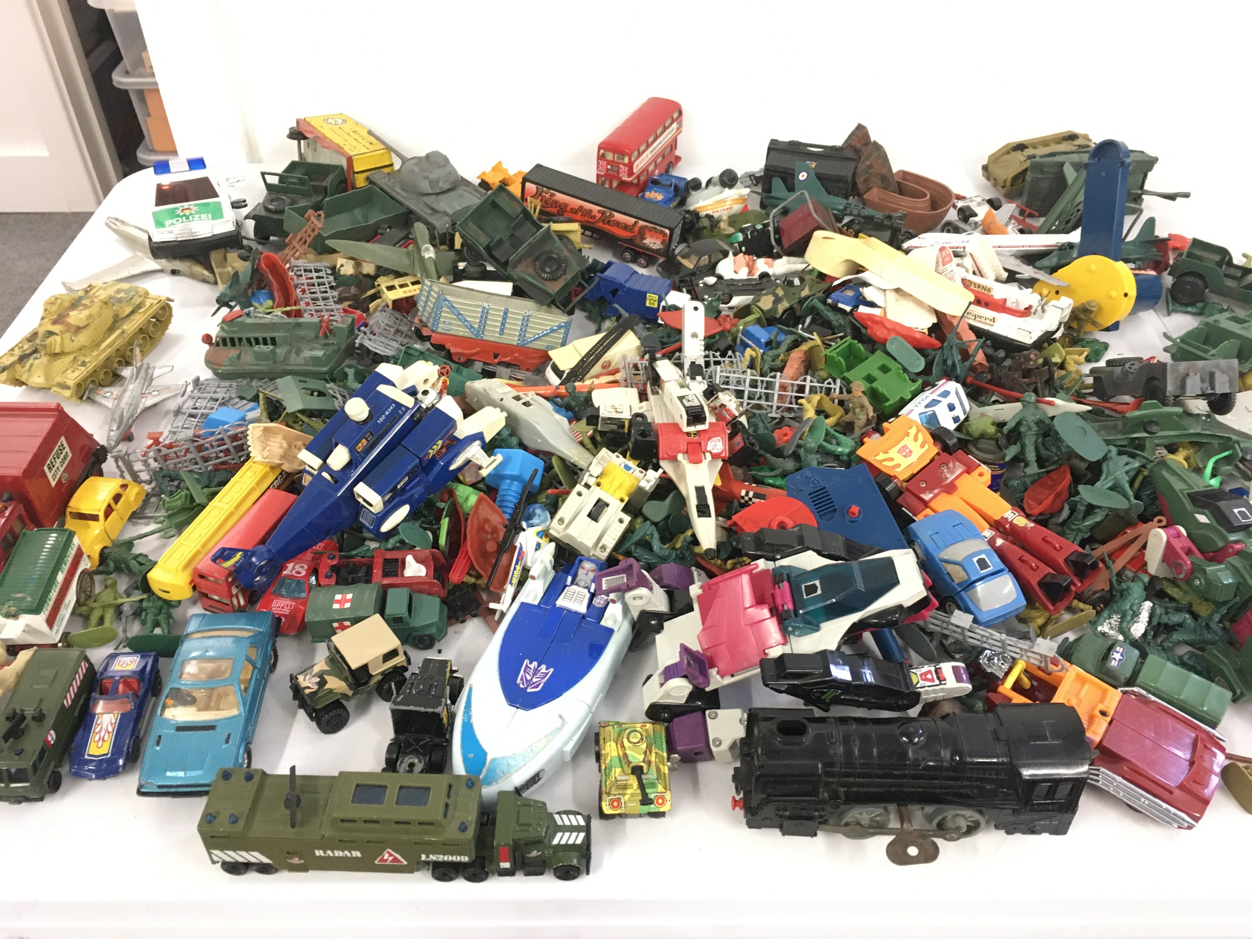 A collection of Playworn diecast and plastic vehicles including some military items. Clockwork train and tinplate tank. Also includes and some transformer style pieces and planes. Also some plastic toy soldiers included. No reserve
