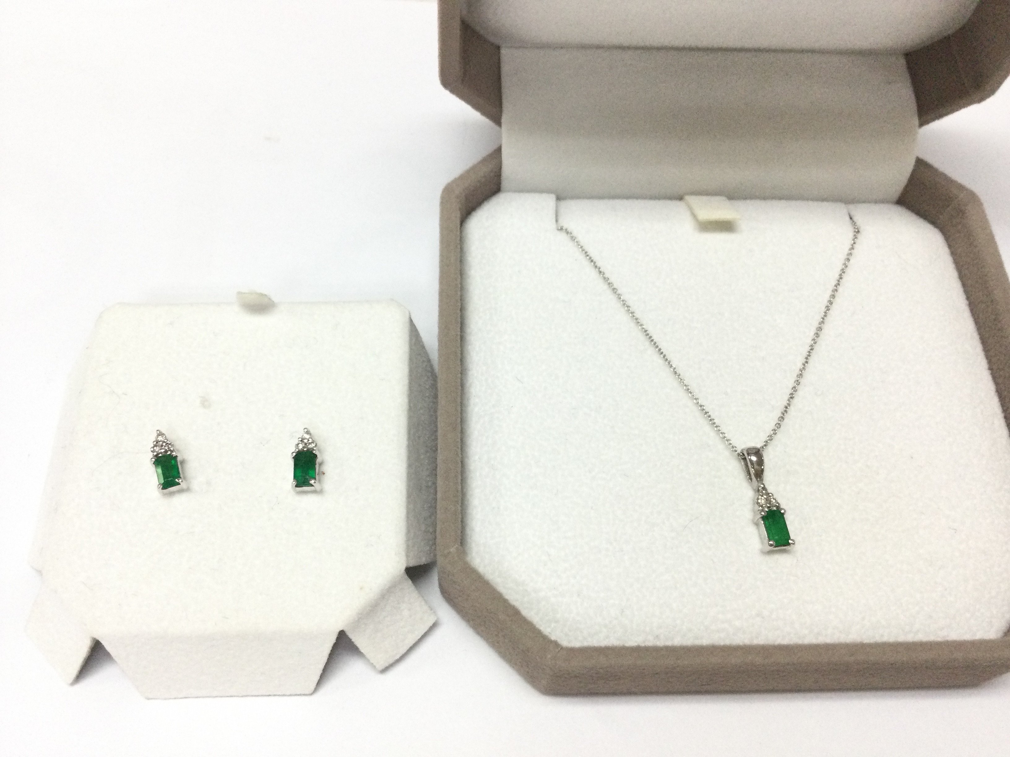 An 14ct white gold emerald and diamond pendant and chain with a matching pair of stud earrings. Postage B