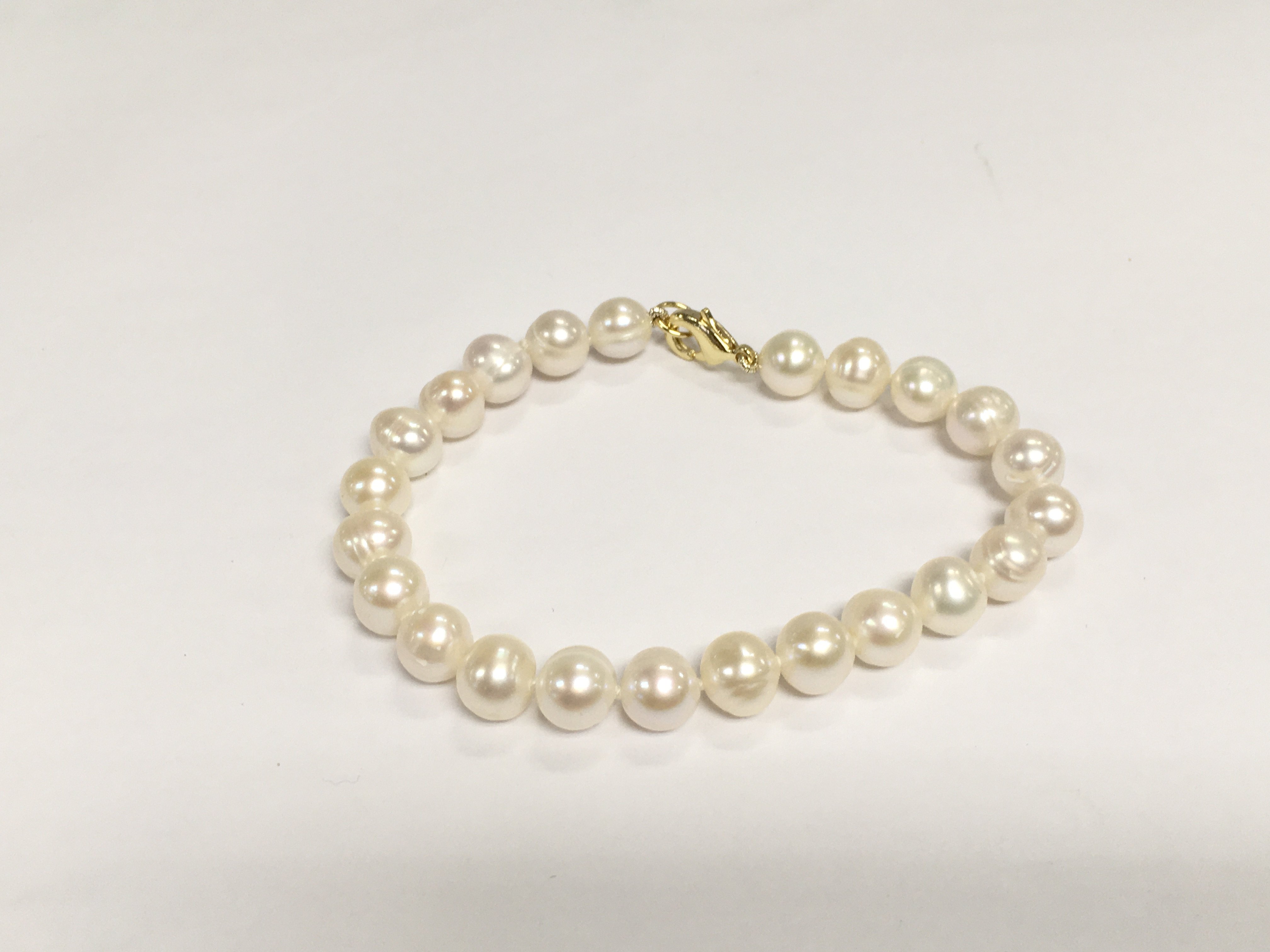 A bracelet strung with white cultured pearls with a gold plated clasp. Shipping category A.
