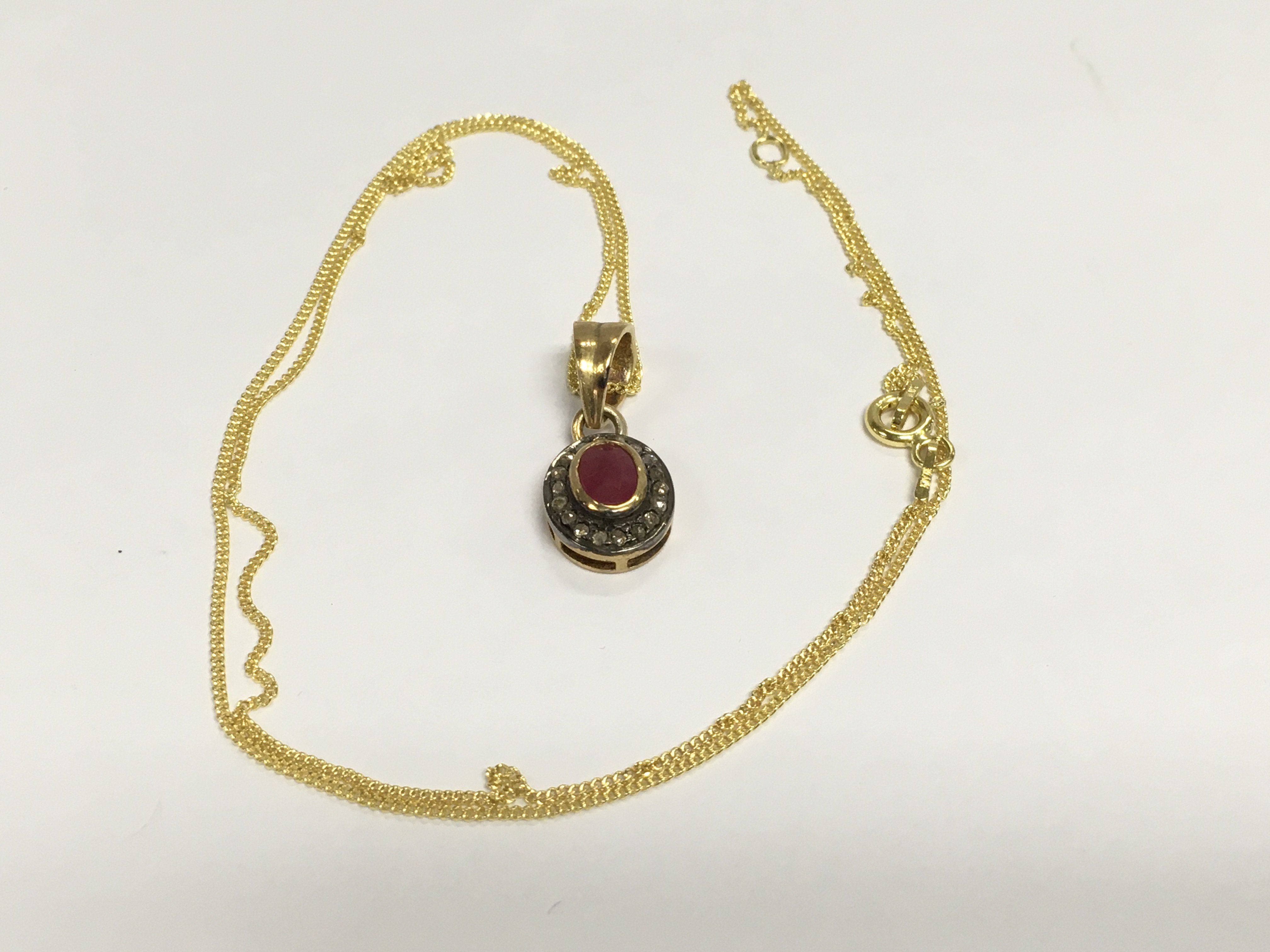An oval ruby and R/C diamond halo gold plated silver pendant on a gold plated chain. Shipping category A.