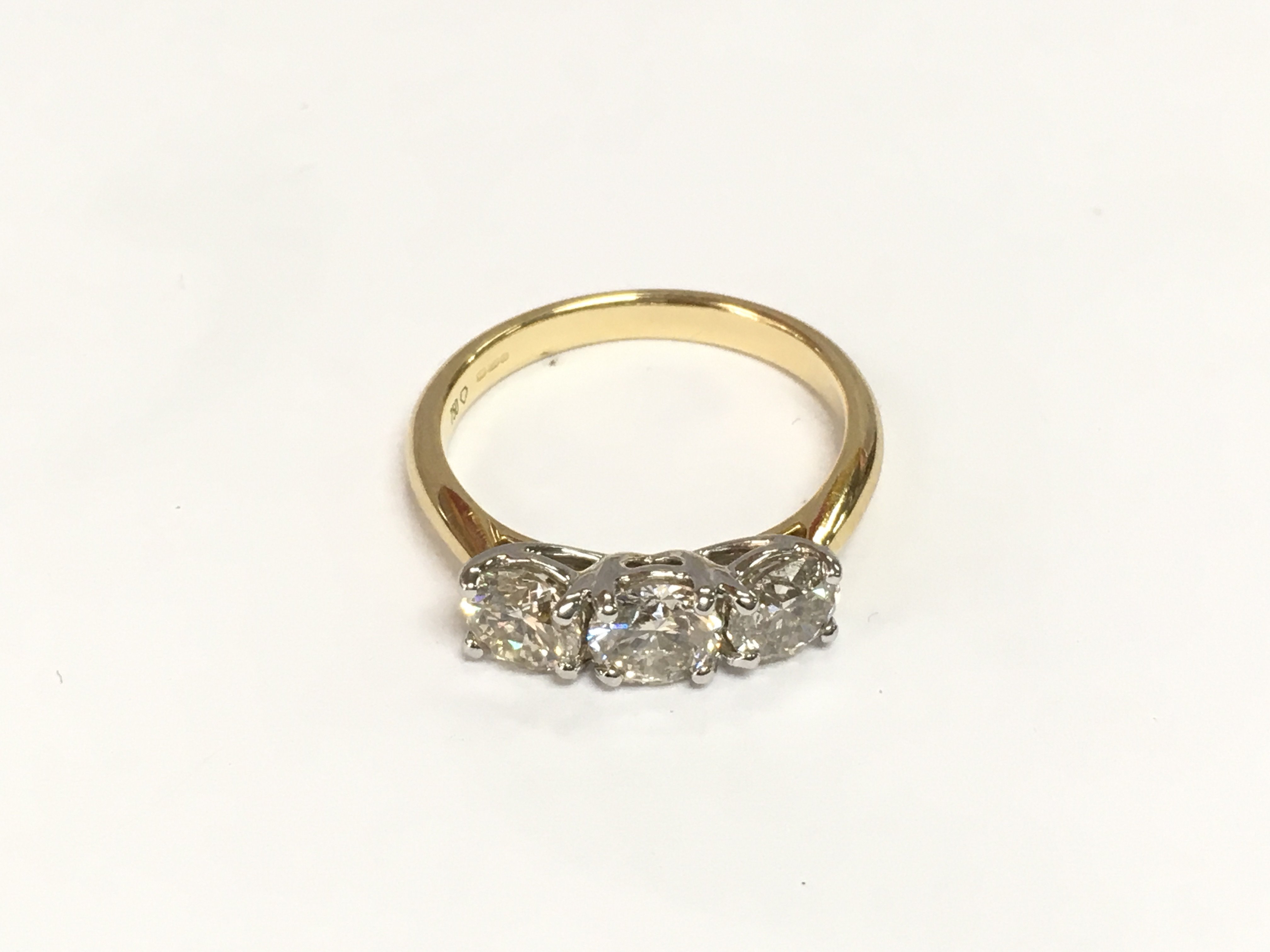 A certificated 18ct white and yellow gold RBC diamond three stone ring. Diamonds approx 1.55ct. Approx 3.7g and approx size M. Cert no WGI9634164256. Shipping category A.