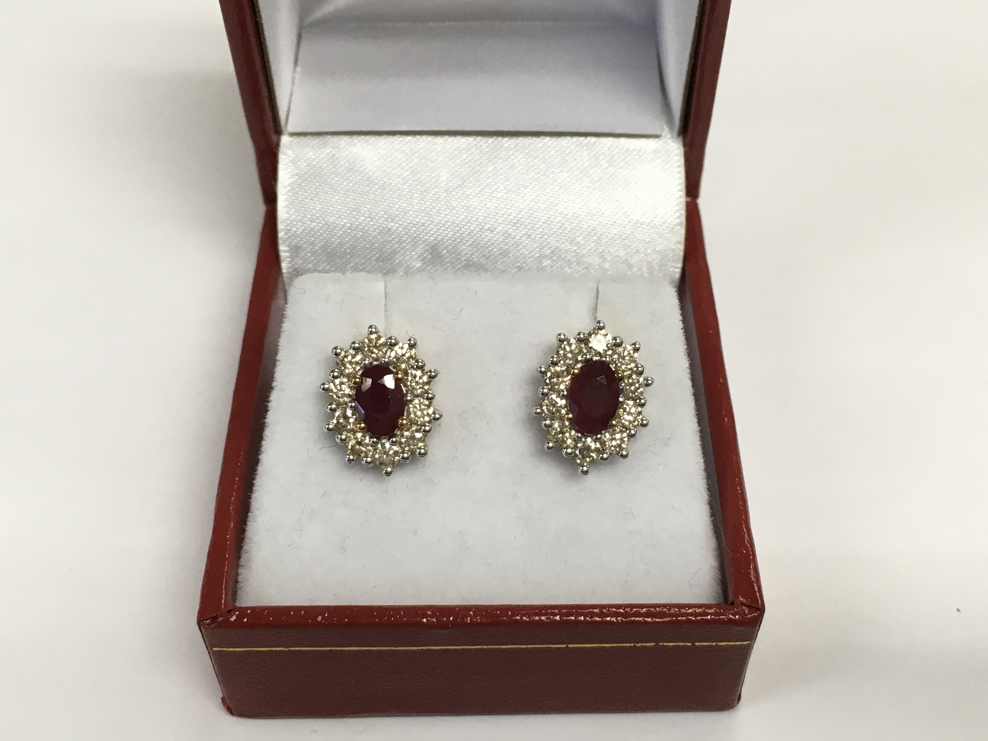 A pair of 9ct yellow and white gold oval ruby and RBC diamond cluster studs. Rubies approx 1.43ct and diamonds approx 1.00ct. Approx 3.6g. Shipping category A.