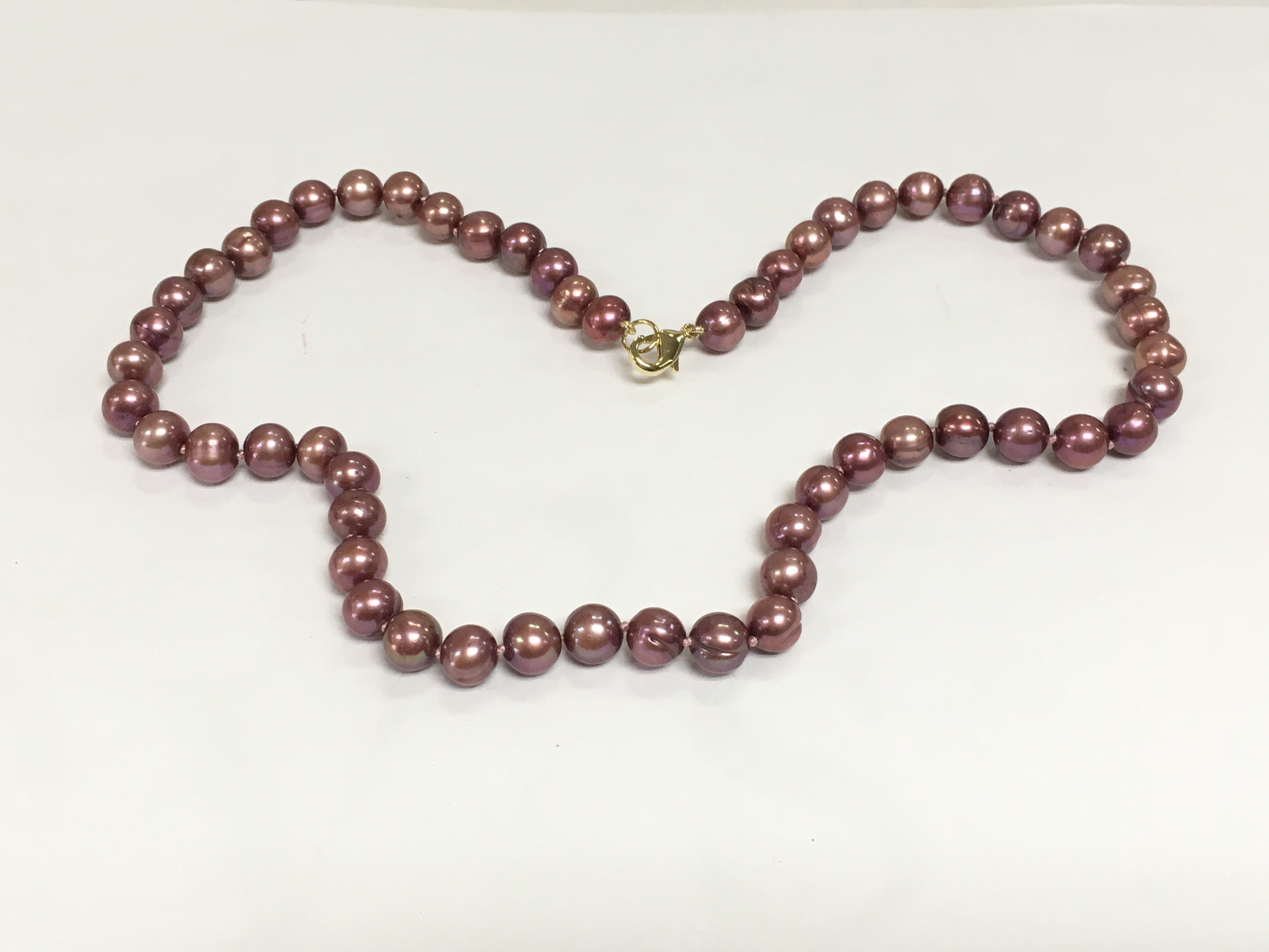 A dark pink/purple cultured pearl necklace with gold plated clasp, approx length 44cm. Shipping category A.