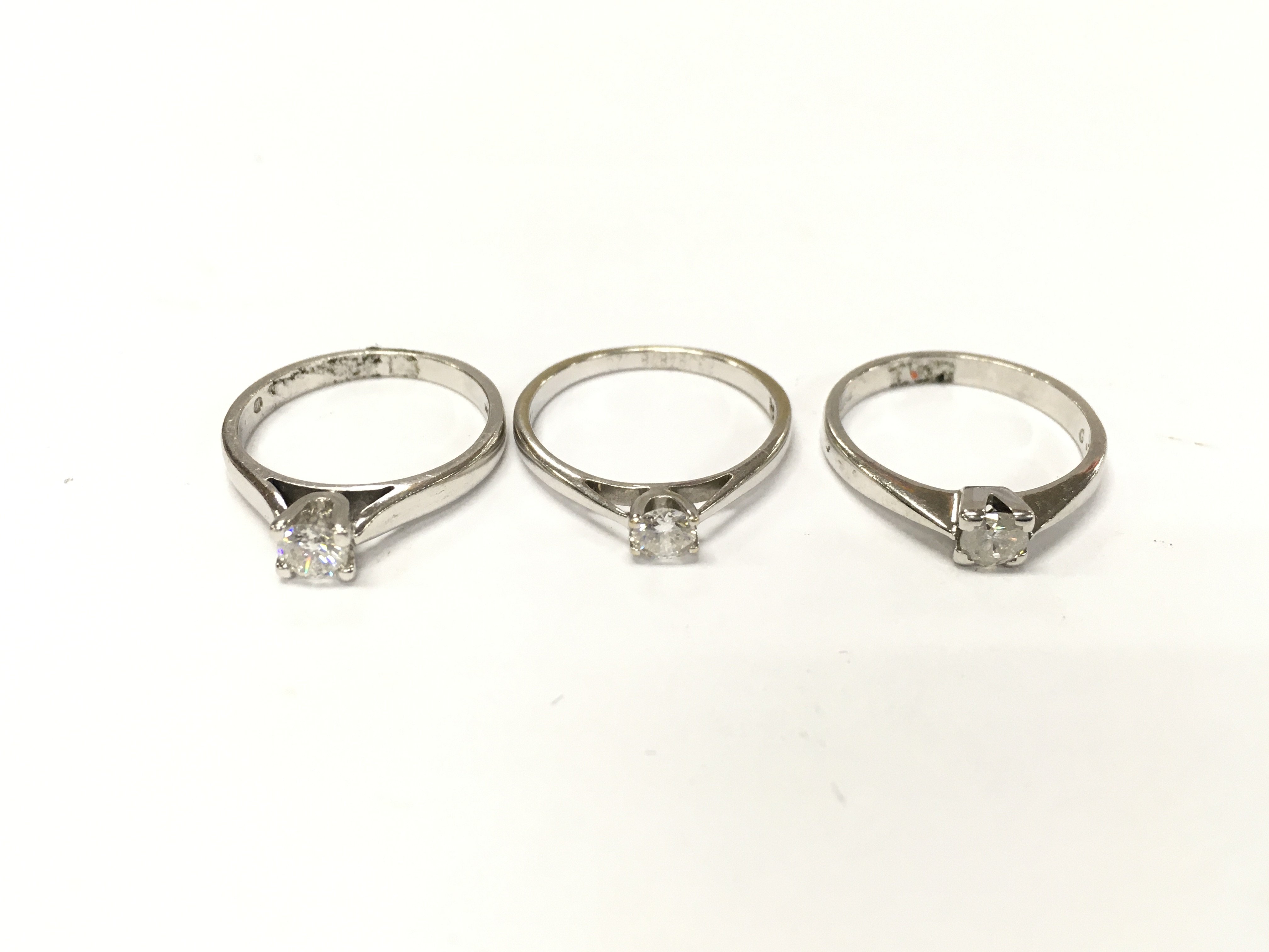 Three 18ct white gold diamond solitaire rings. Sizes L and M and approximately 8.1g total