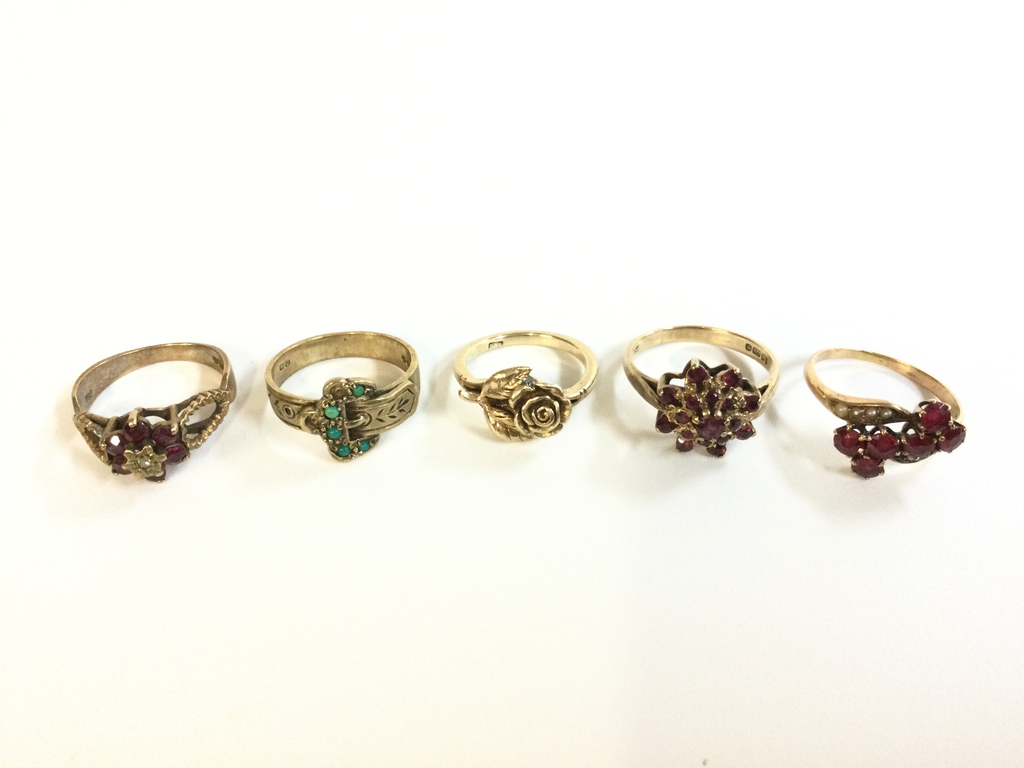 Five 9 carat gold rings , ruby stone set designs and one rose design . Sizes N, J, P. Total weight 14.6g . Postage category A