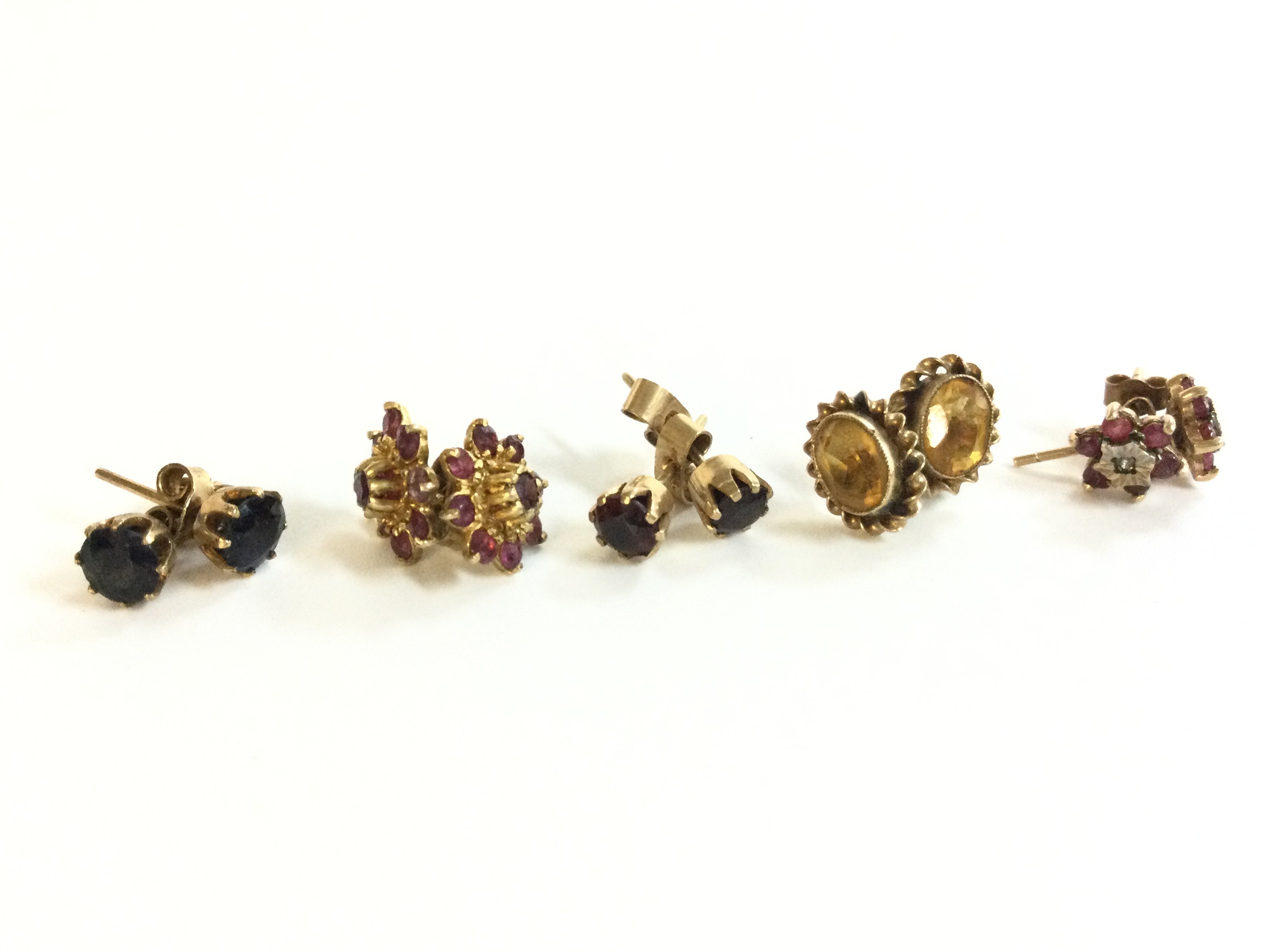 A collection of gold earrings set with various stones including black sapphires and rubies . 7.2g total weight. Postage category A