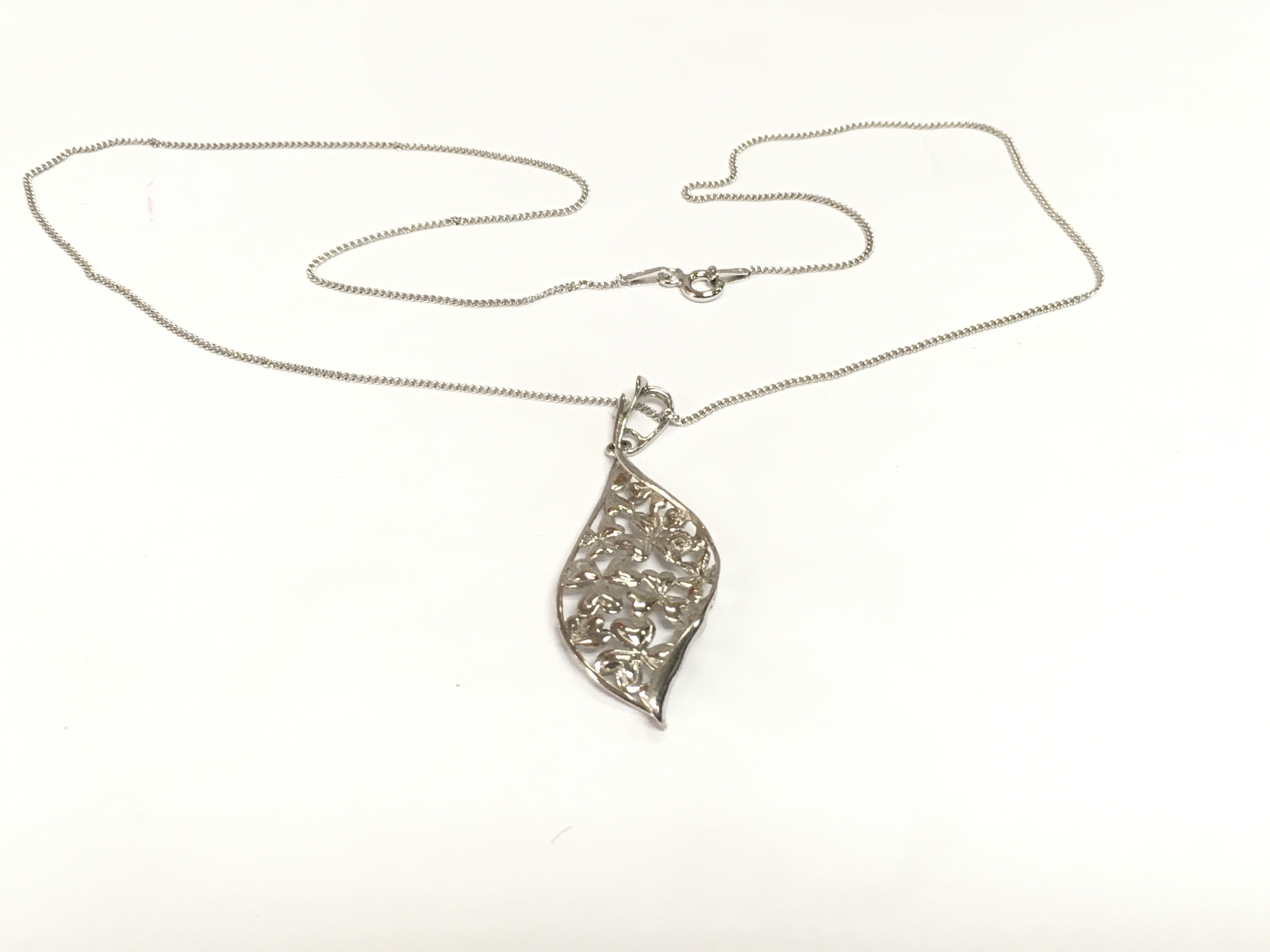 A silver leaf shaped pendant with heart details and suspended on a silver chain. Shipping category A.