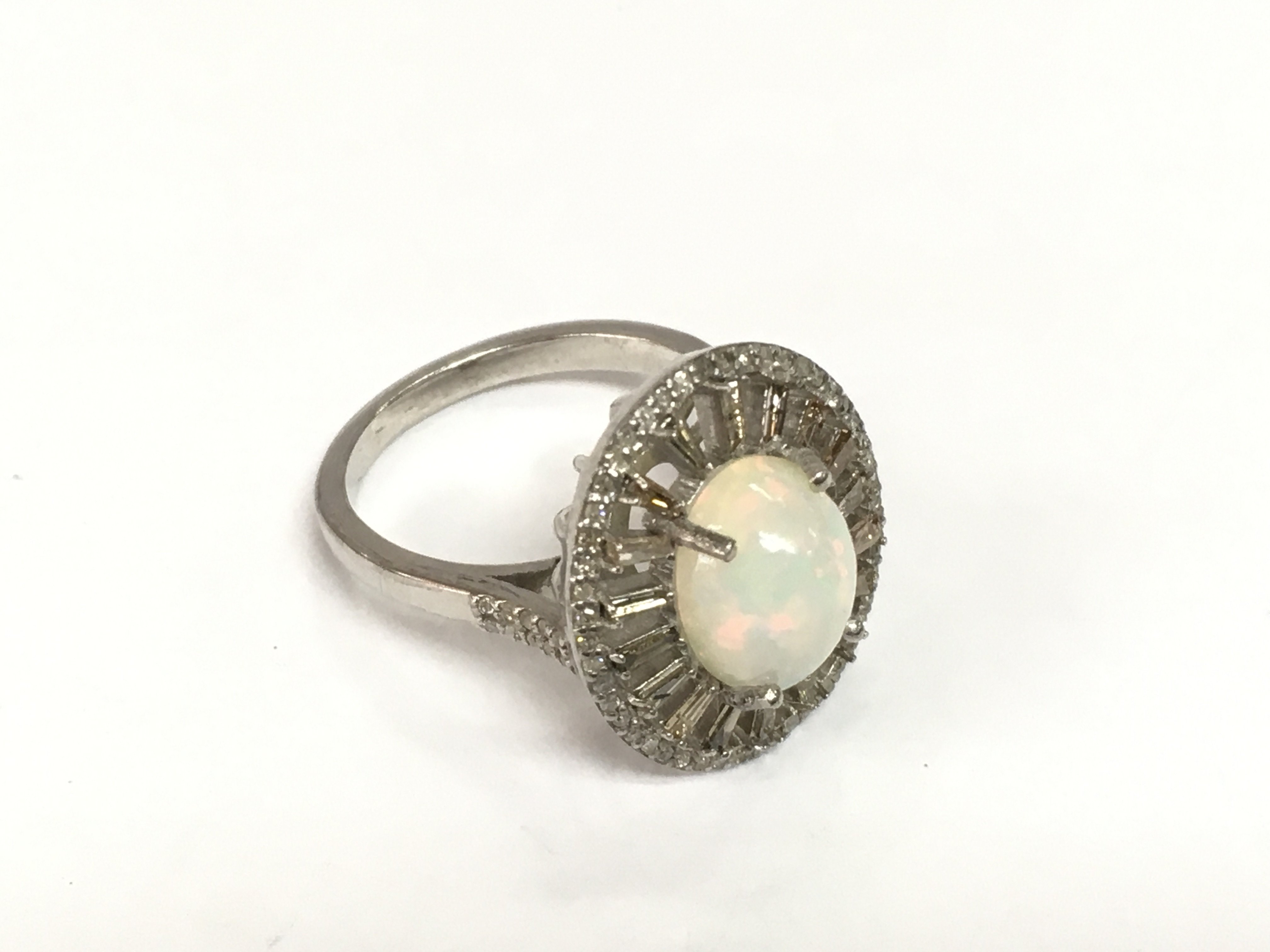 A silver ring set with an oval cabochon opal, tapered and round diamonds. Opal approx 1.85ct, diamonds approx 0.62ct. Approx size N. Shipping category A.