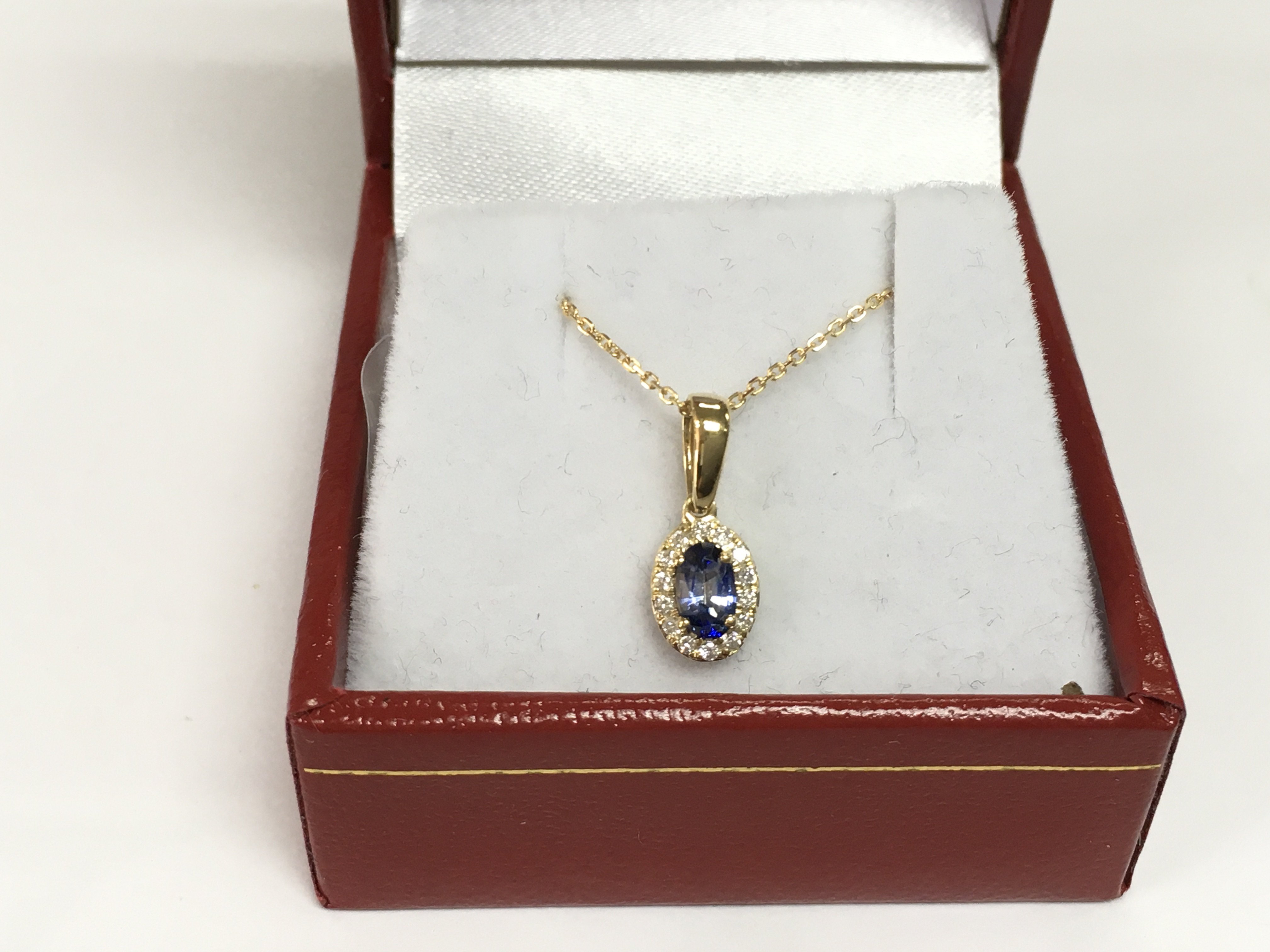 A 9ct yellow gold oval sapphire and RBC diamond cluster pendant on a 9ct yellow gold chain. Sapphire approx 0.31ct, diamonds approx 0.07ct. Approx 1.5g. Shipping category A.
