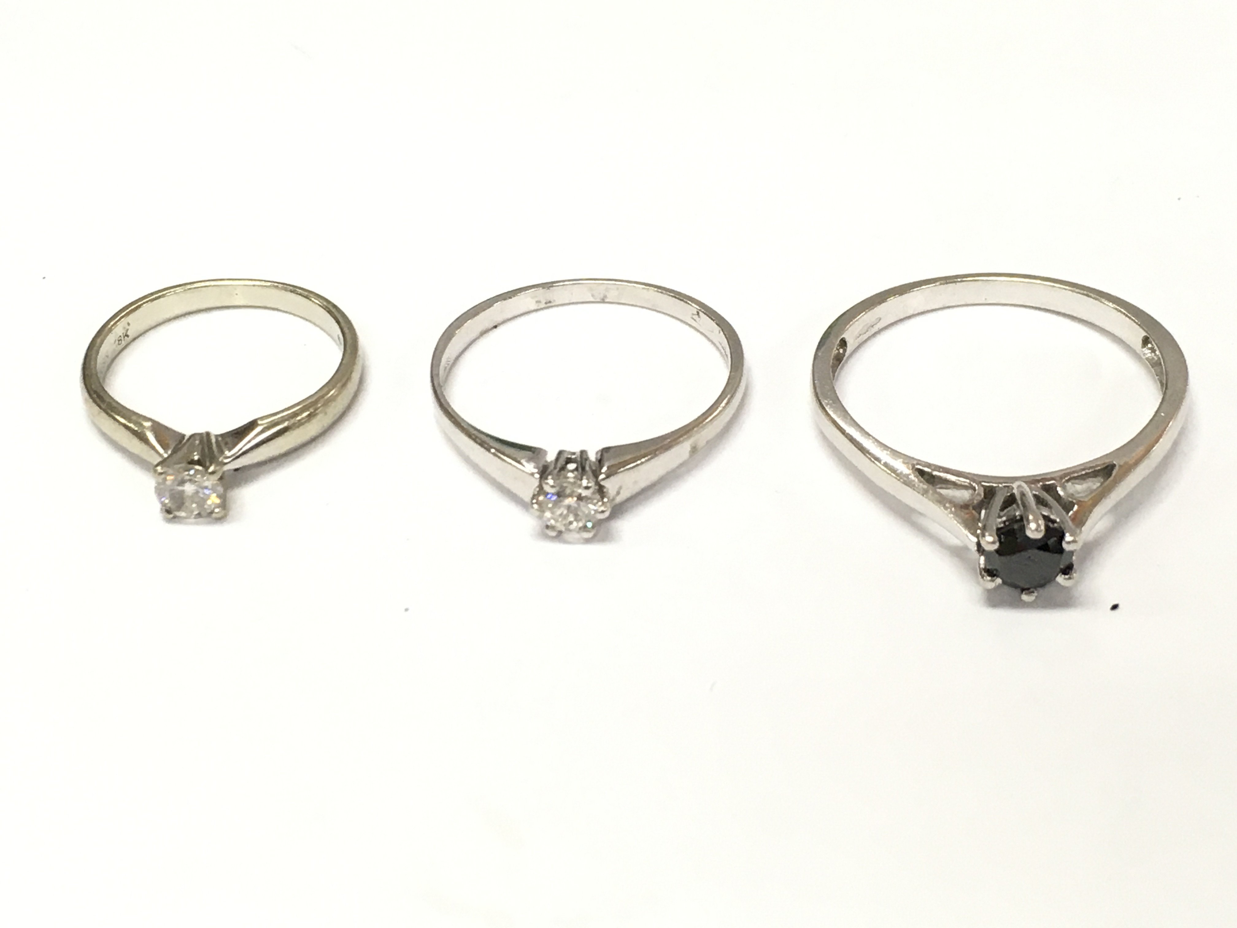 Three 18ct white gold diamond solitaire rings one with black diamond. Sizes H O T and approximately 7.3g