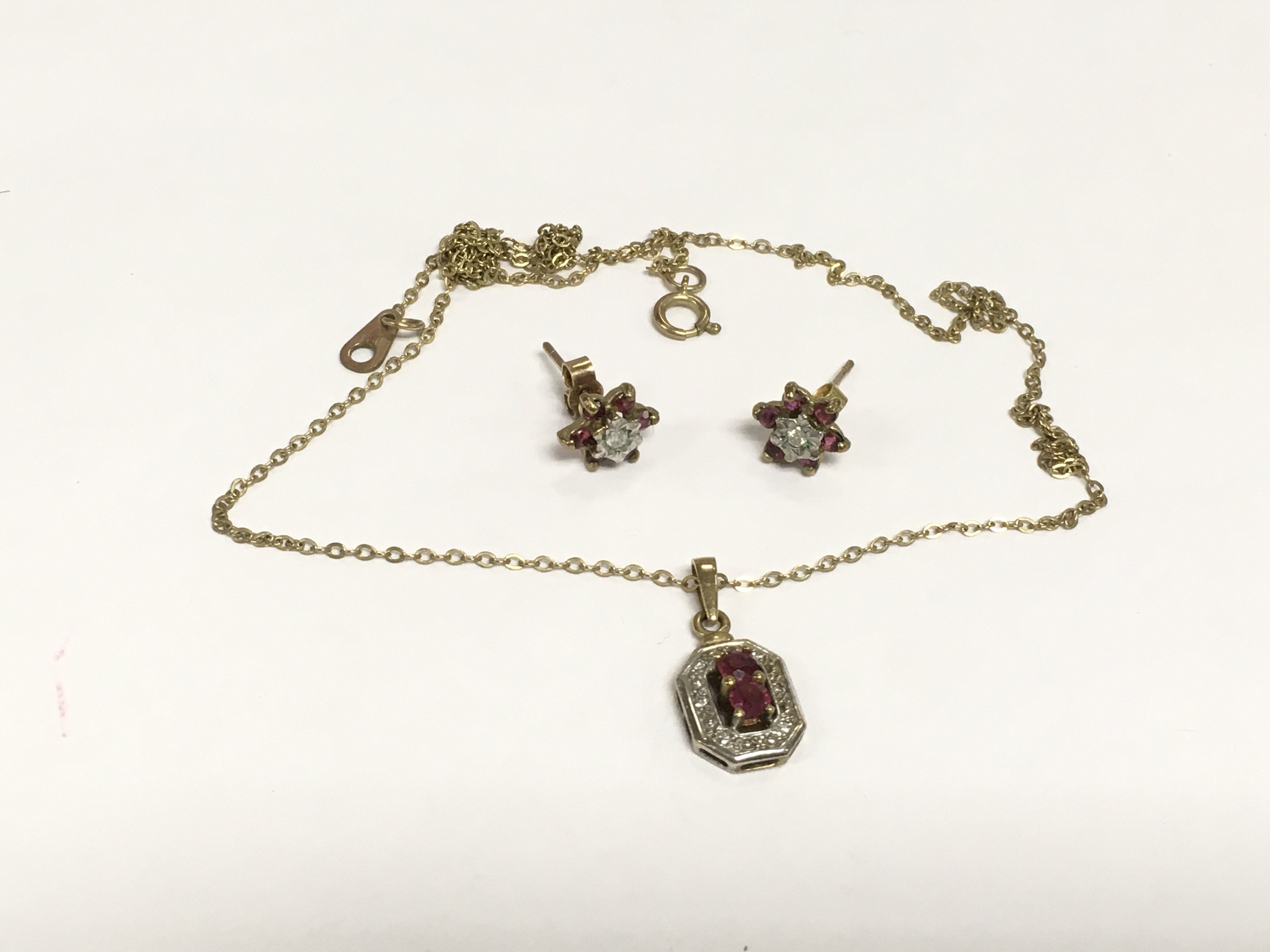 A 9ct gold diamond and garnet pendant on a gold chain and a matching pair of earrings. Approx total weight 3.4g. Shipping category A.