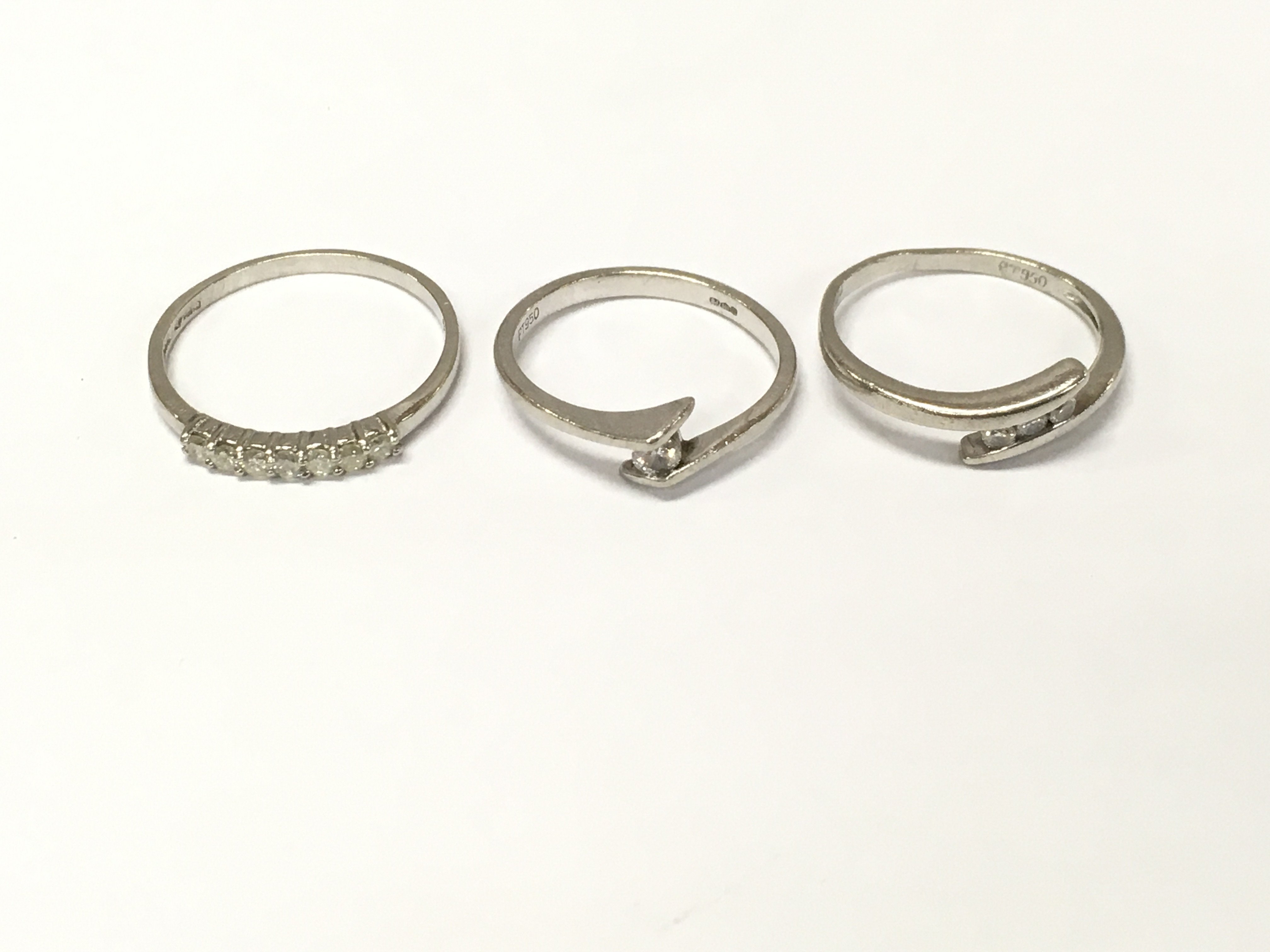 Three platinum diamond rings of various designs. Sizes J M P approximately 8g