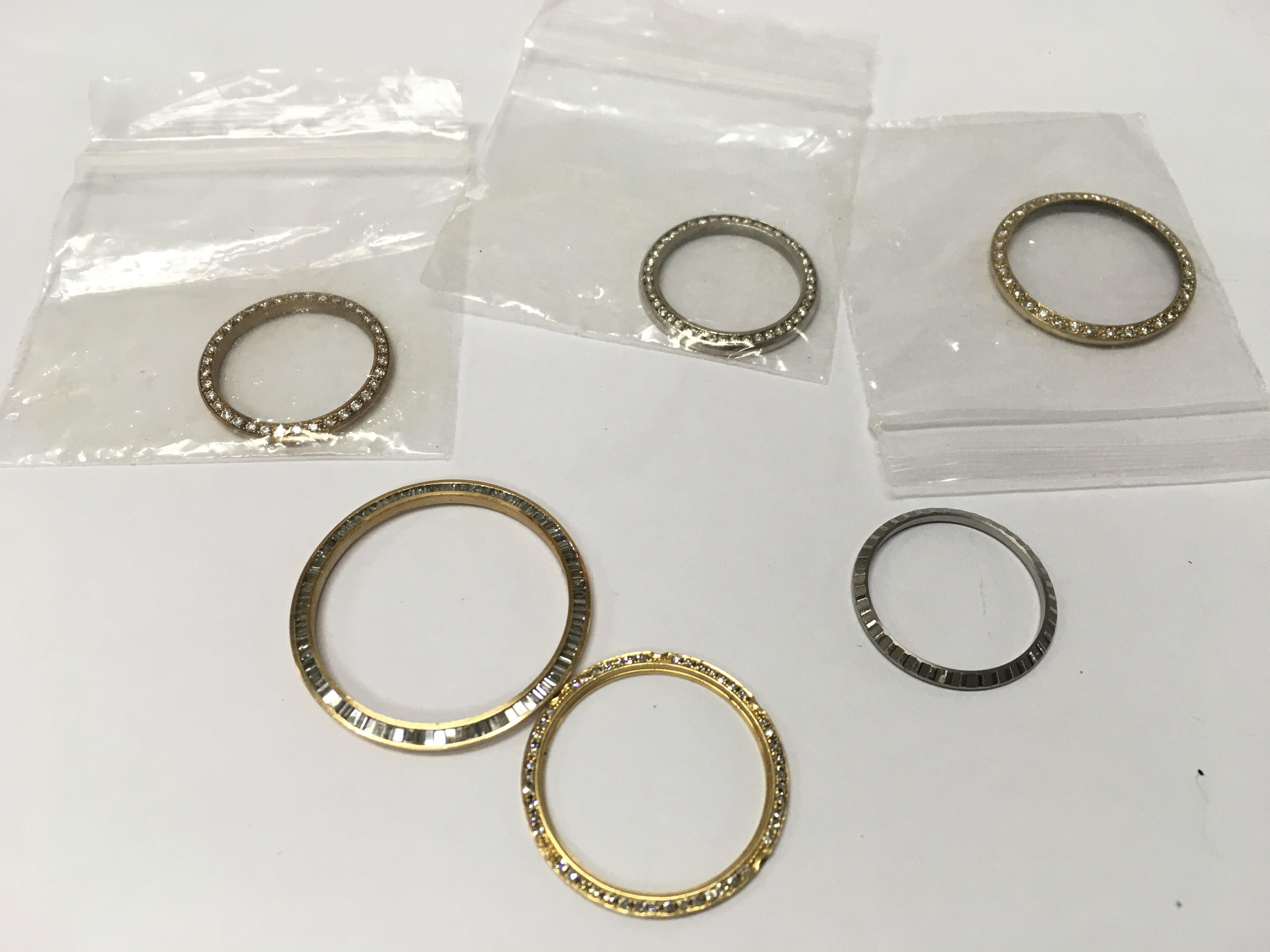 A collection of rolex style bezels including diamond set.