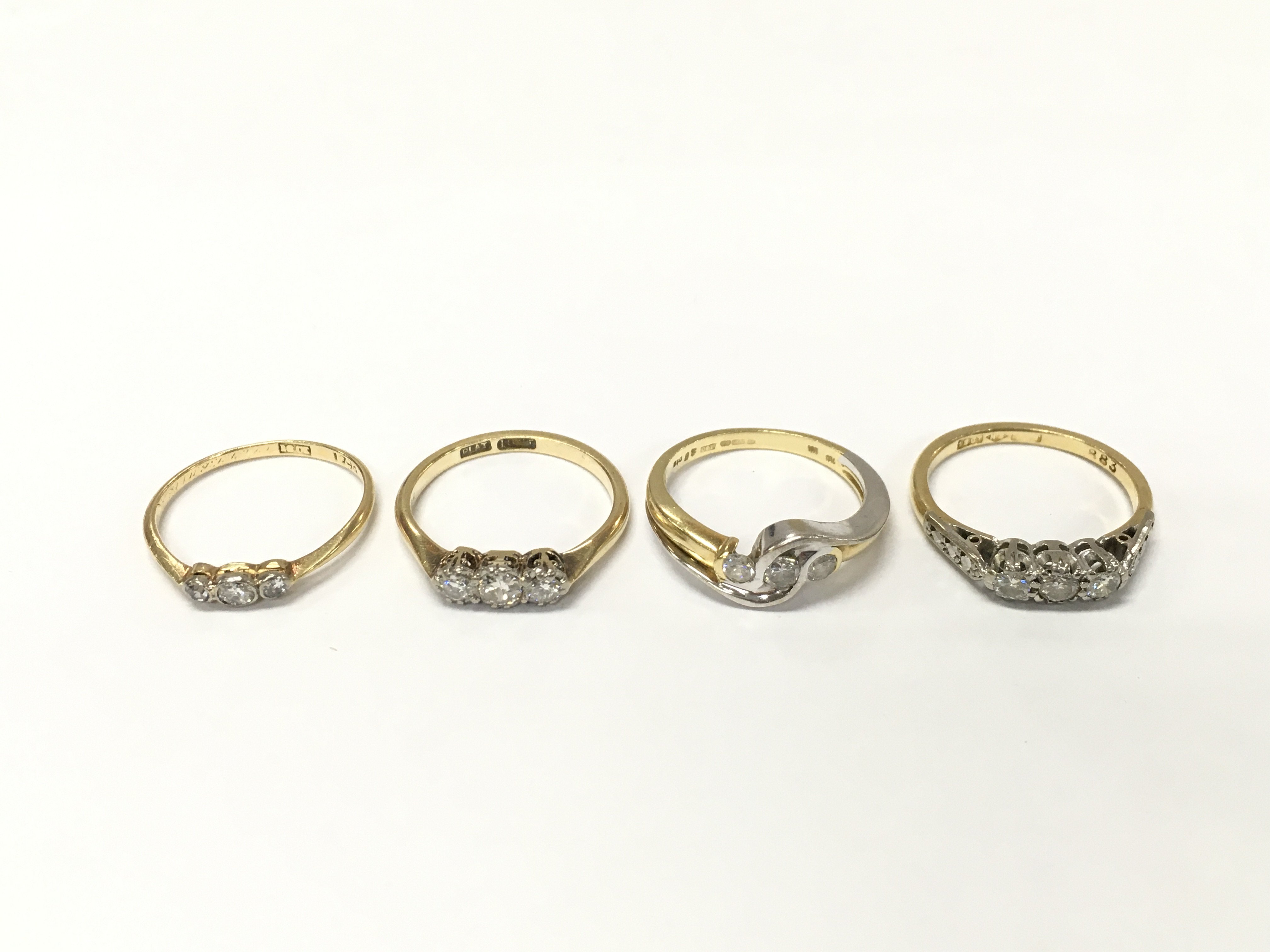 Four 18ct gold diamond three stone rings. Sizes K and K 1/2 approximately 10.4g