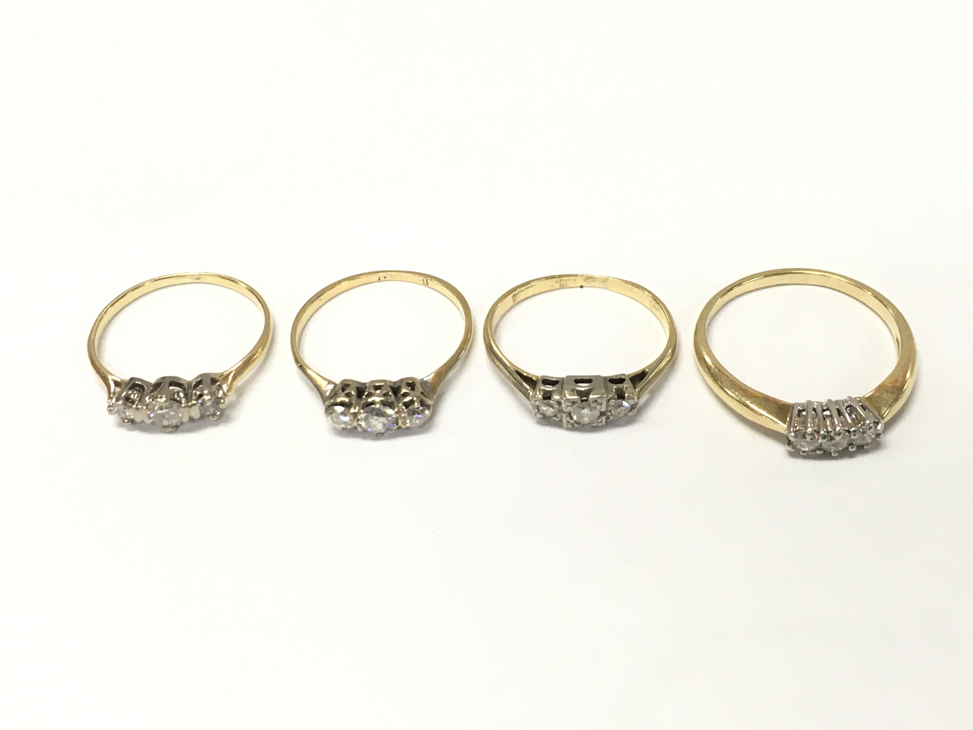 Four unmarked yellow metal three diamond rings. Sizes M N and R approximately 8g