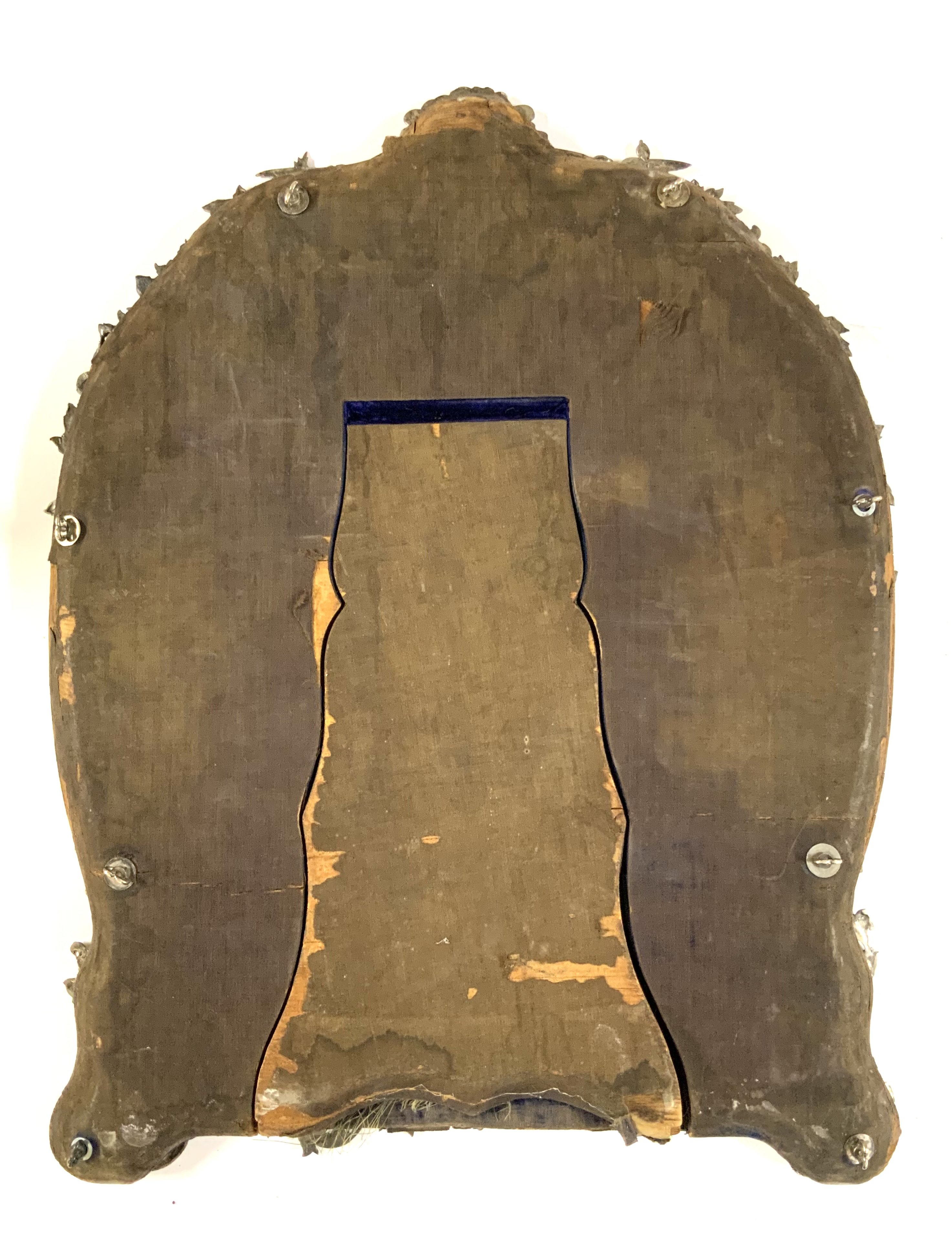 An Antique Victorian hallmarked Sterling Silver dressing table mirror having hand-chased angels, God&#2013266057_s and Goddesses, scroll-work, and floral decoration, with a top engraved cartouche, an original bevelled heart-shaped mirror on a blue velvet backing with easel stand. Made by William Comyns of London in 1887. Height. 51.5cm x 37cm.