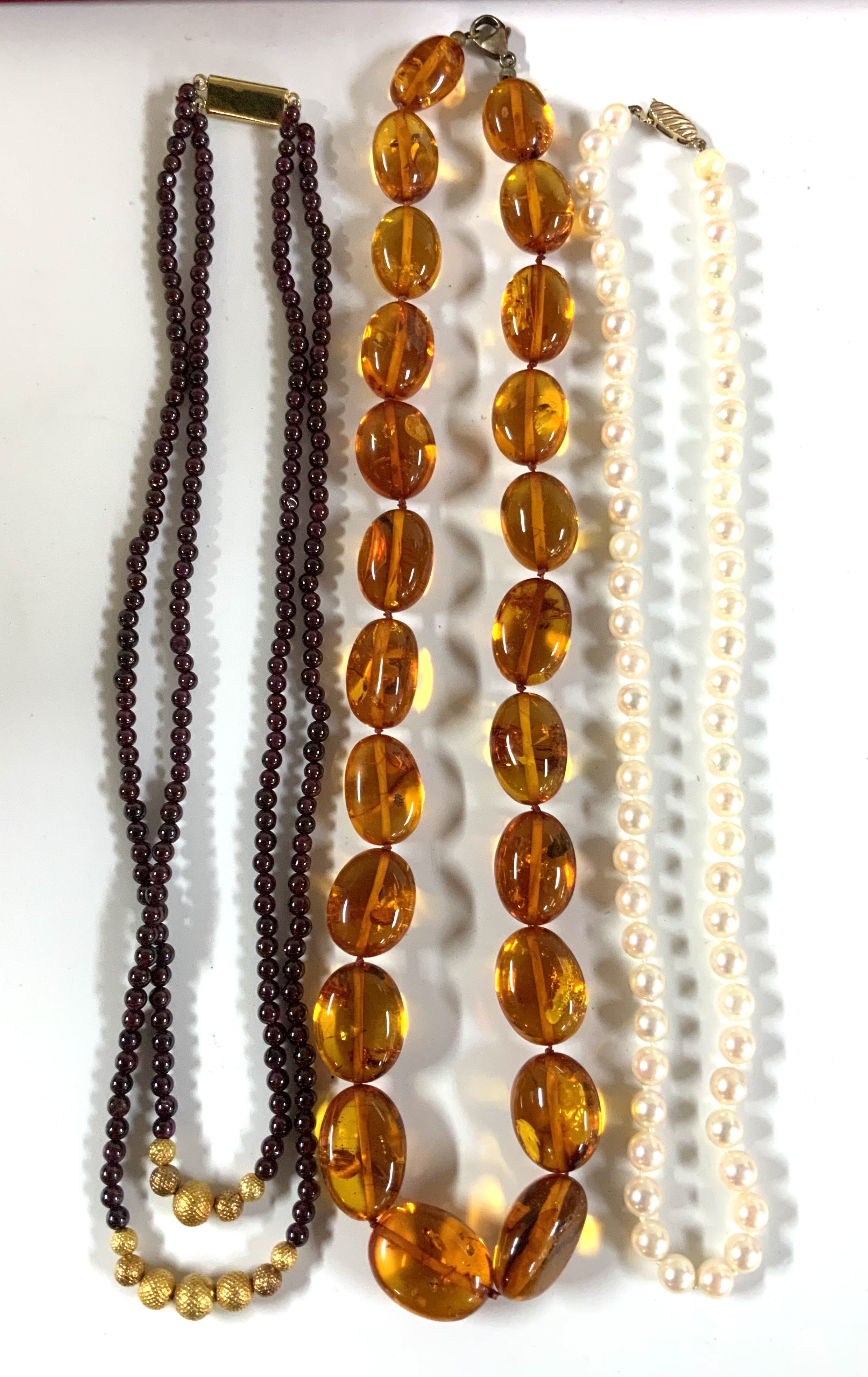 A vintage Amber bead necklace, cultured pearl necklace, eastern garnet and gilt bead necklace. (A)