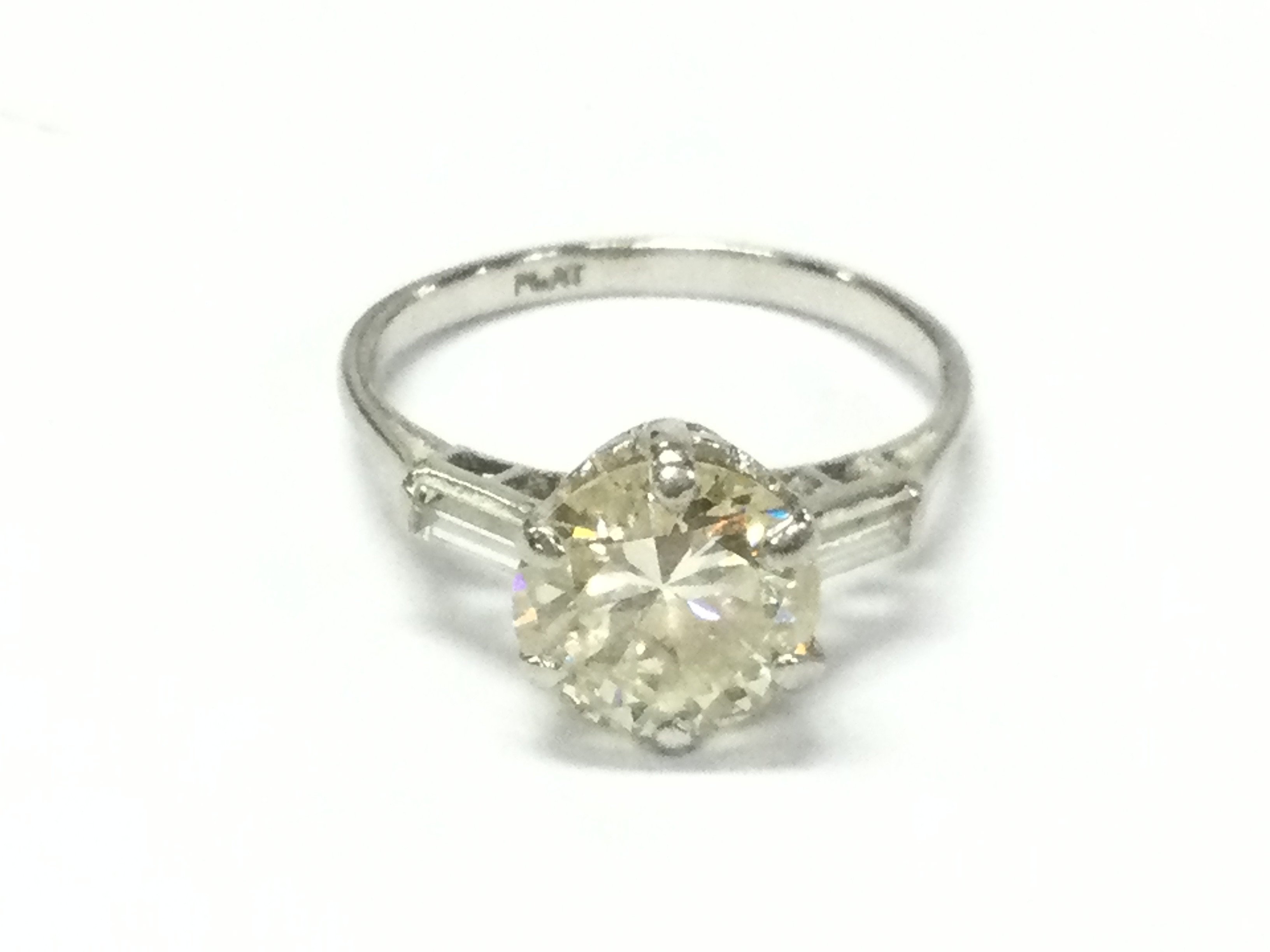 A platinum set diamond ring with 2.55ct round cut central stone and baguette cut diamond shoulders. VS2 and M colour.