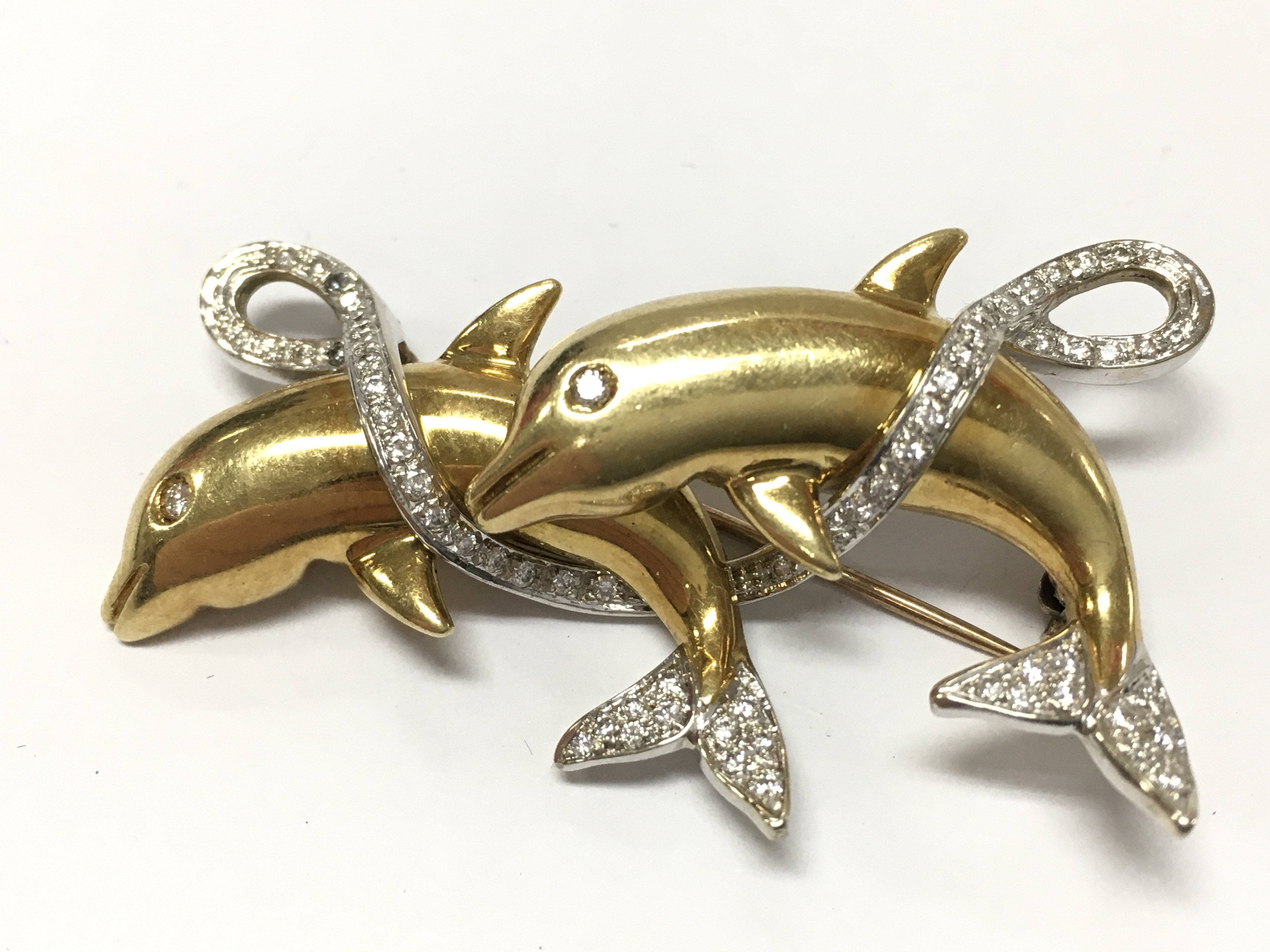 An unmarked gold dolphin brooch set with diamond stones , 14.5g total weight. Postage category A