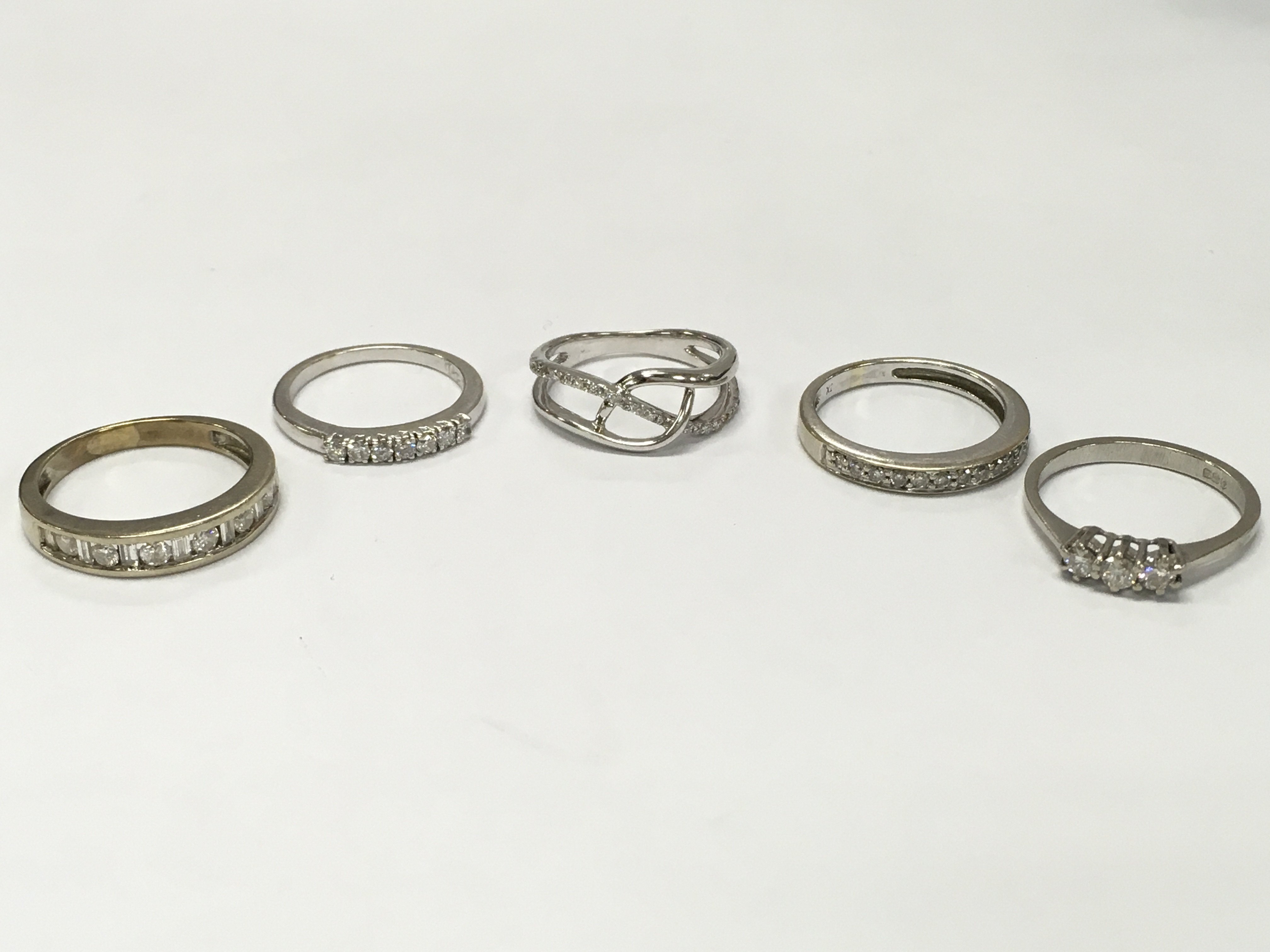 A Collection of high carat unmarked white gold white stone set rings (10g total weight) and a silver ring. Sizes I, M. 12.8g total weight. Postage cat a