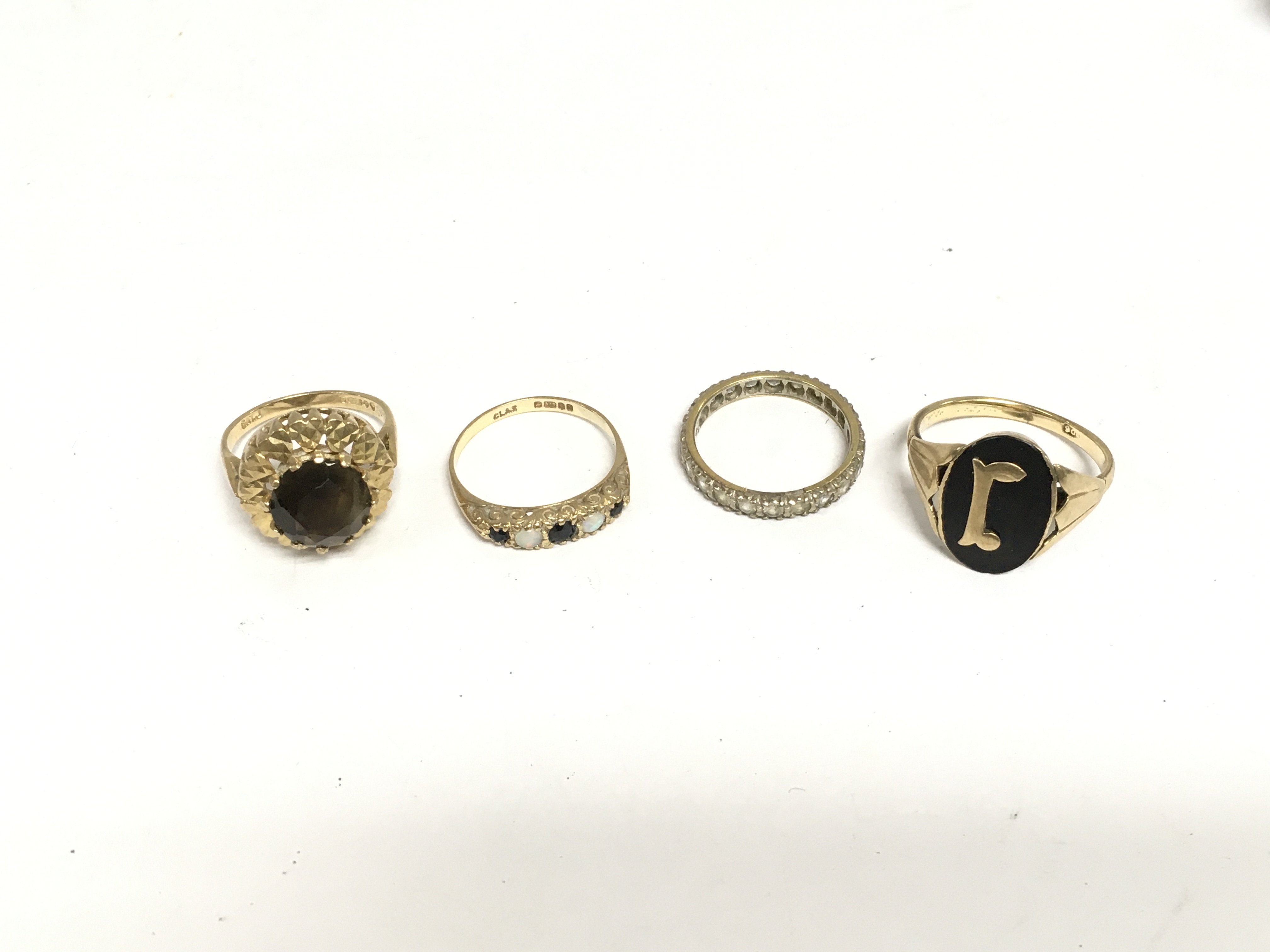 Four gold rings comprising an 18ct gold eternity ring, one set with opals and sapphires plus two others. Total approx 14g. Shipping category A.