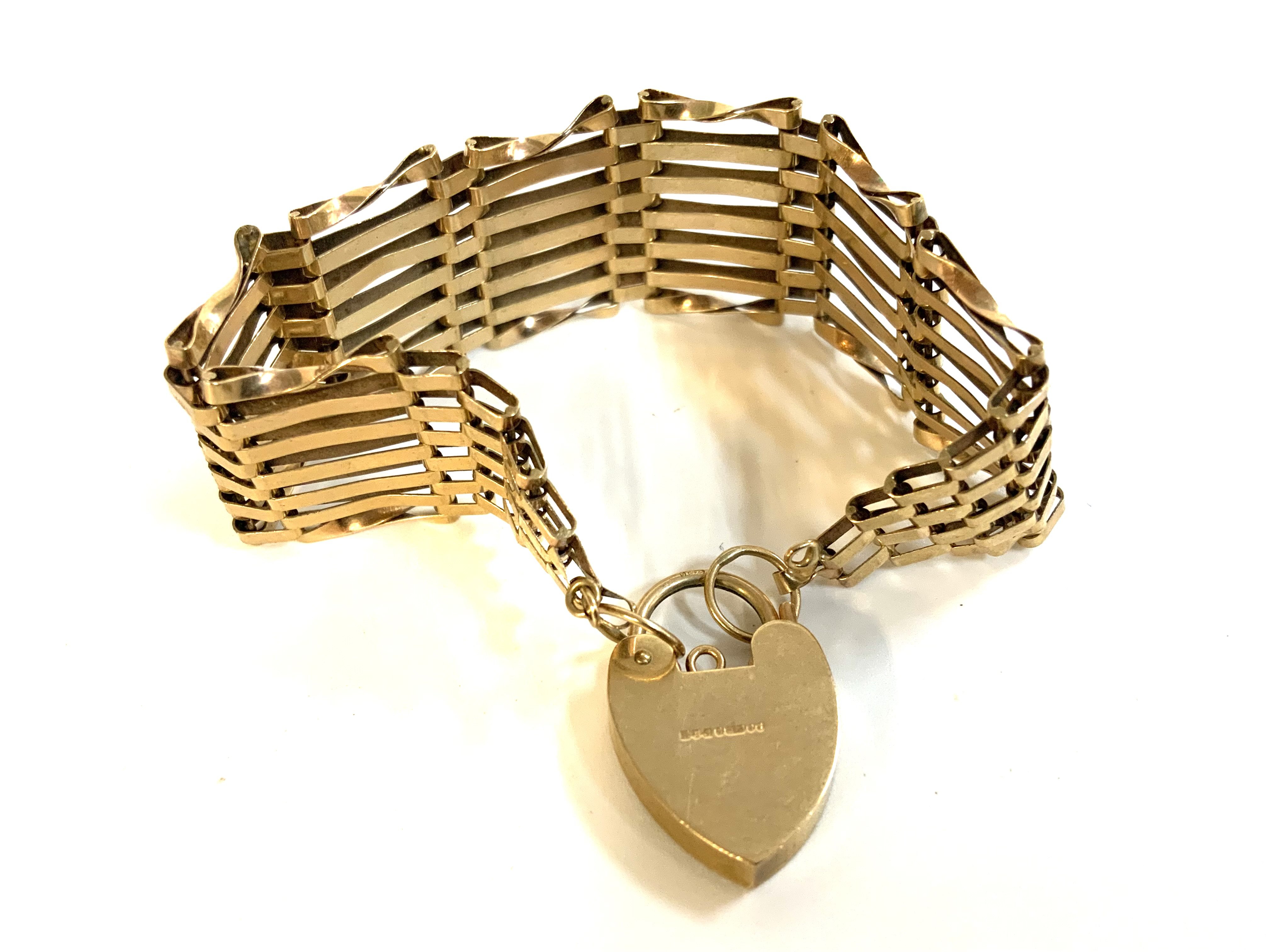 A 9ct gold gate bracelet with heart locket. (A)