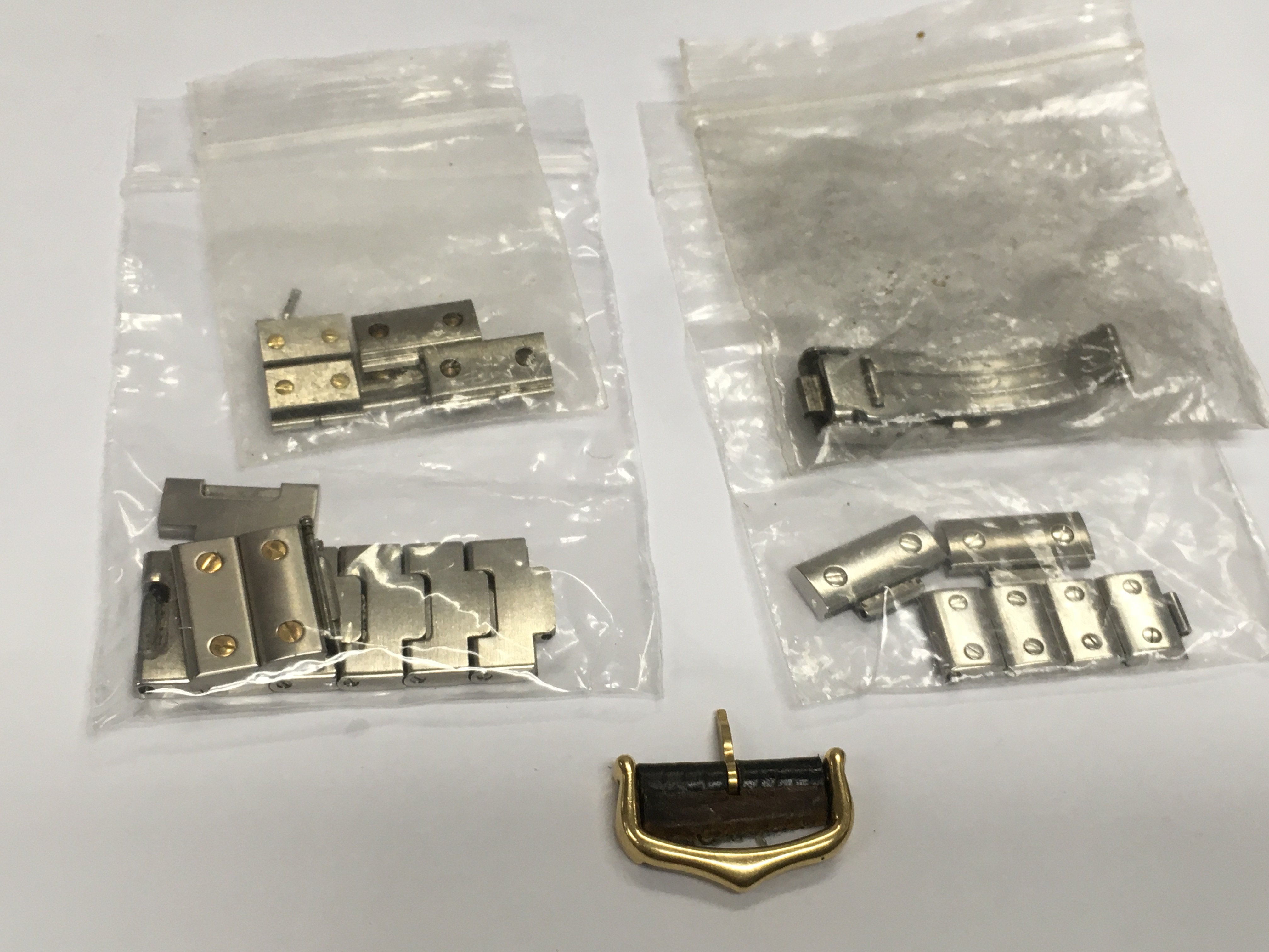 A small collection of spare watch links, an 18ct gold Cartier buckle etc. Shipping category A.