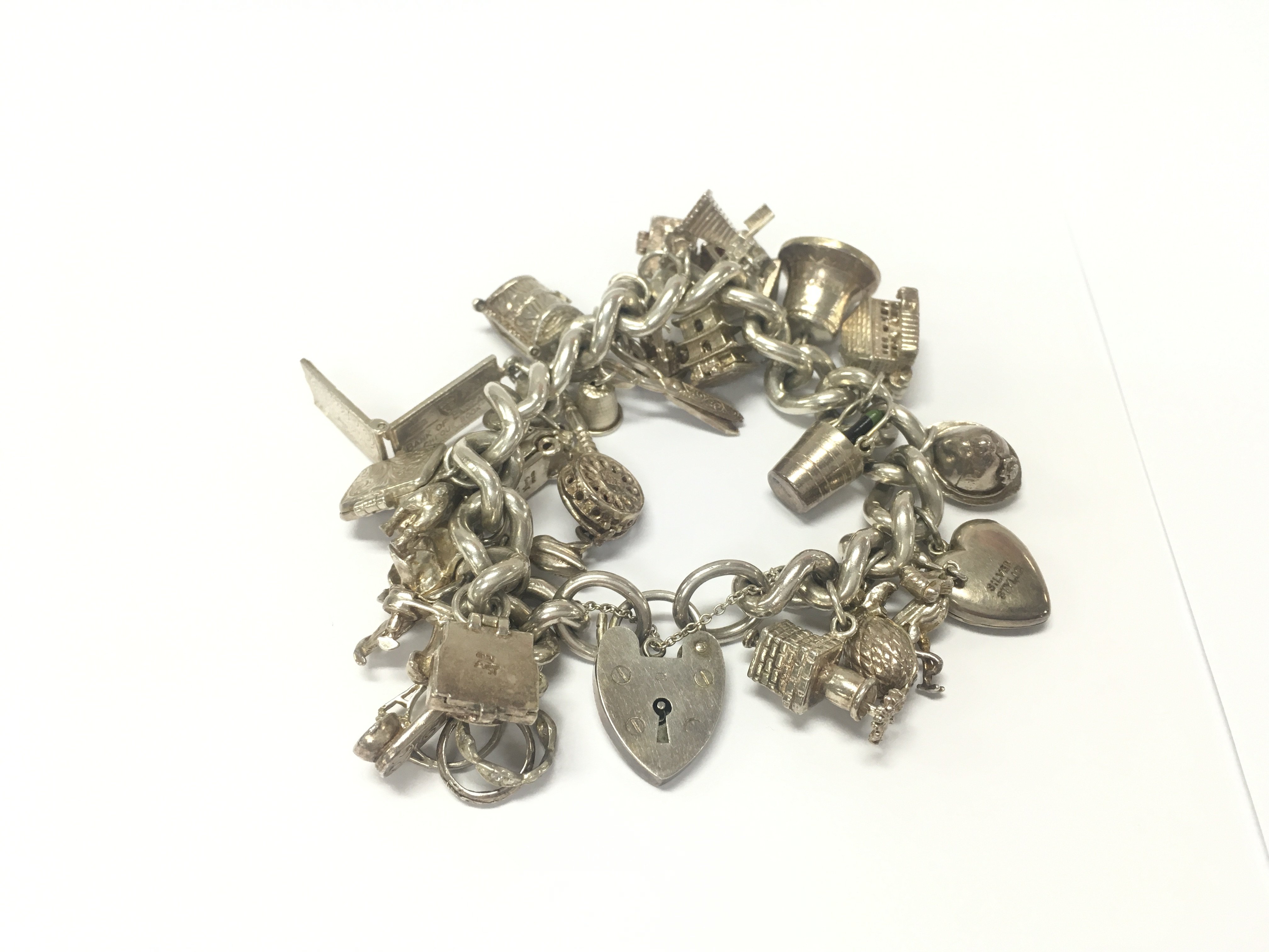 A heavy silver charm bracelet set with a large number of silver charms. Approximately 140g