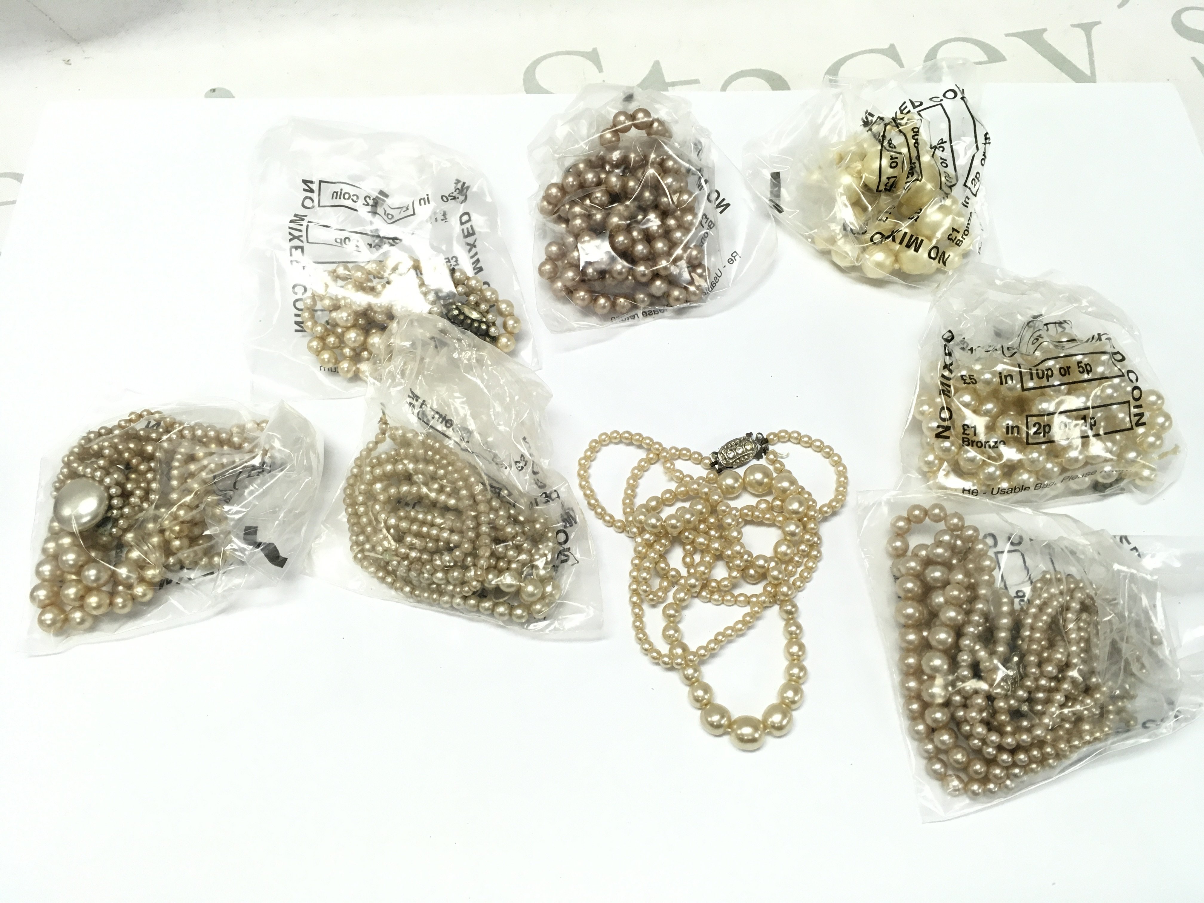 A Collection of simulated pearl necklaces . Postage category A