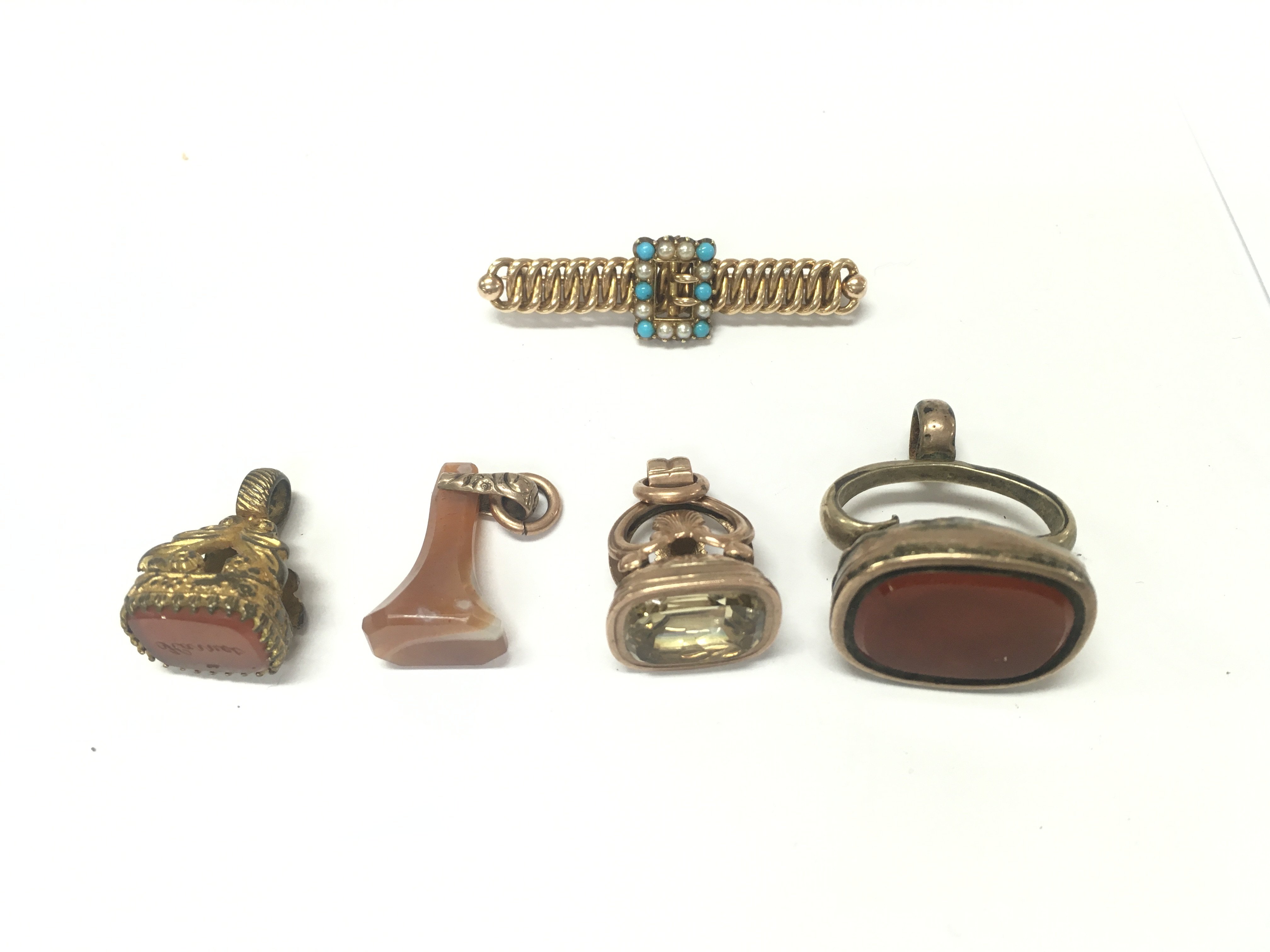 Four antique seals of various designs and a yellow metal brooch.