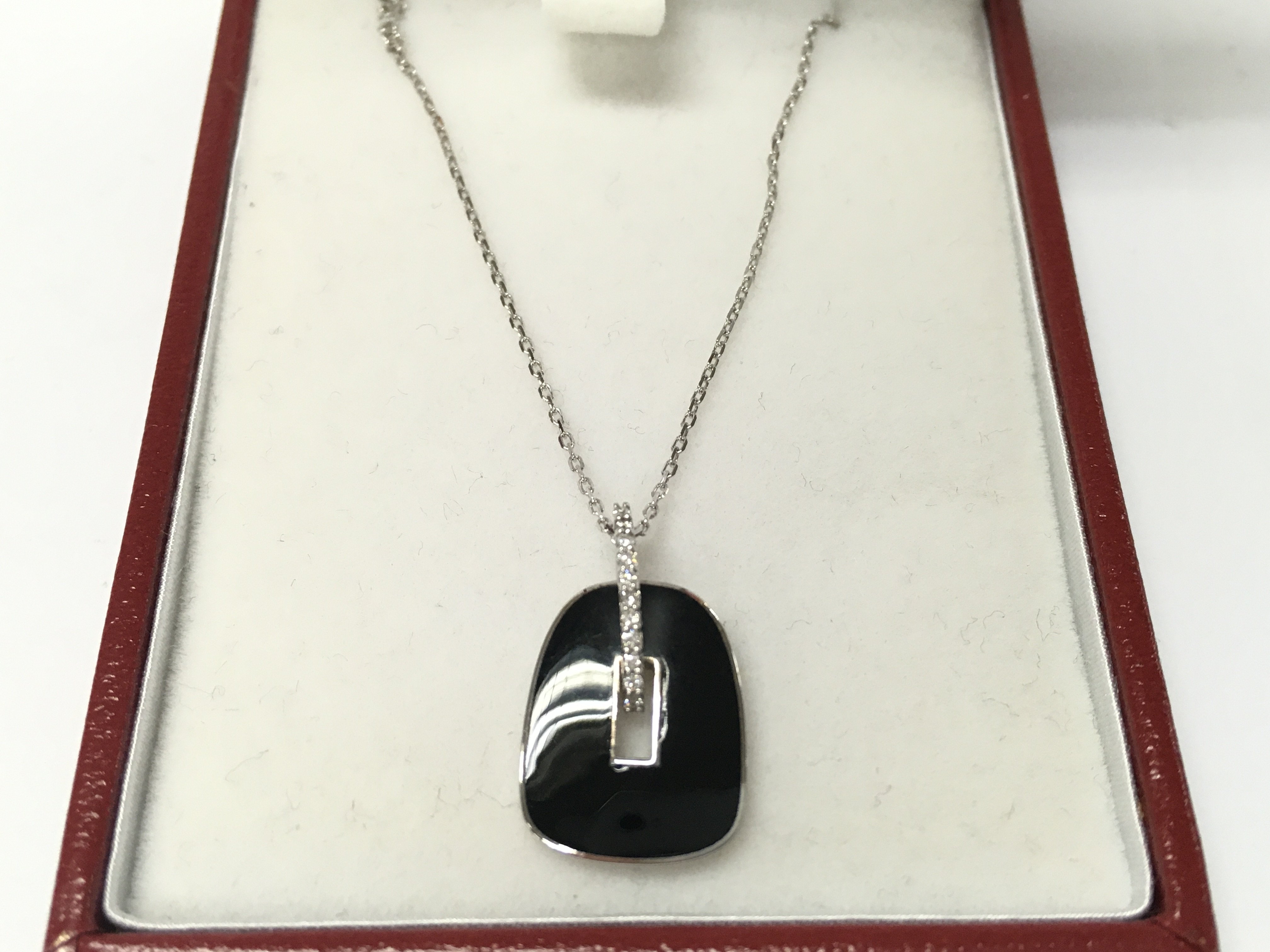 A 14ct white gold necklace with black enamel and diamonds pendant.