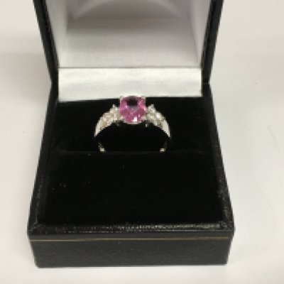 An 18ct white gold trilogy ring set with an oval pink sapphire flanked by six RBC diamonds. Sapphire approx 1.65ct, diamonds approx 0.27ct. Approx 3.2g and approx size L-M. Shipping category A.