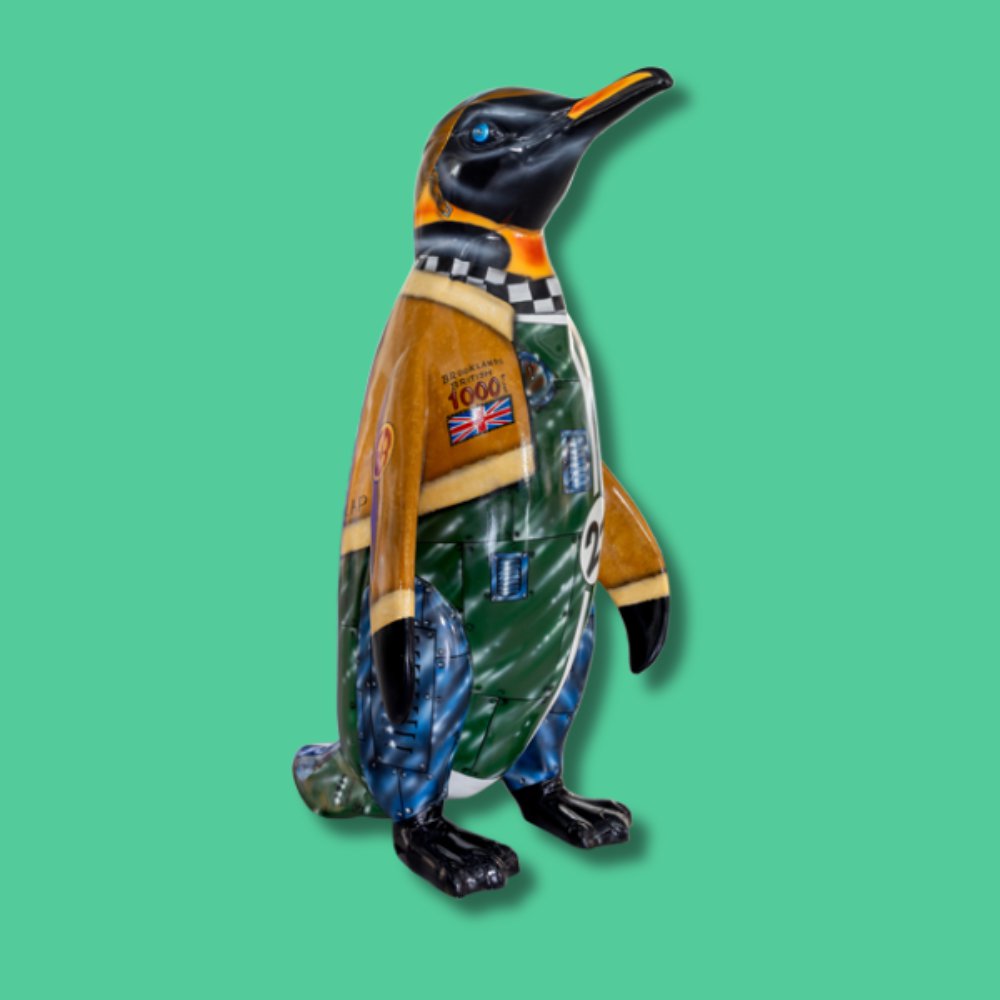 Pole Position - Sponsor: Gateway / Artist: Mik Richardson / Penguins are so sleek and speedy under the water, just like a sports car is on the land. This snappy fella is designed to represent an old 1920s sports car and driver, in shining chrome and racing green complete with a racing number. He has a leather jacket with a flapping scarf, racing emblems and a cool helmet with goggles. With his sleek looks, he is sure to be in Pole Position. Mik is a Norfolk-based artist who has run his own art business since leaving the RAF in 2006. He has produced over 400 murals for schools, communities, and private clients, and painted 110 Wild in Art sculptures for 56 trails. He's also painted 29 sculptures for other trails. In 2018, he illustrated his first children's storybook, based on a Wild in Art sculpture design. - Height 1600mm width 890mm Depth 1090mm weight 30kg