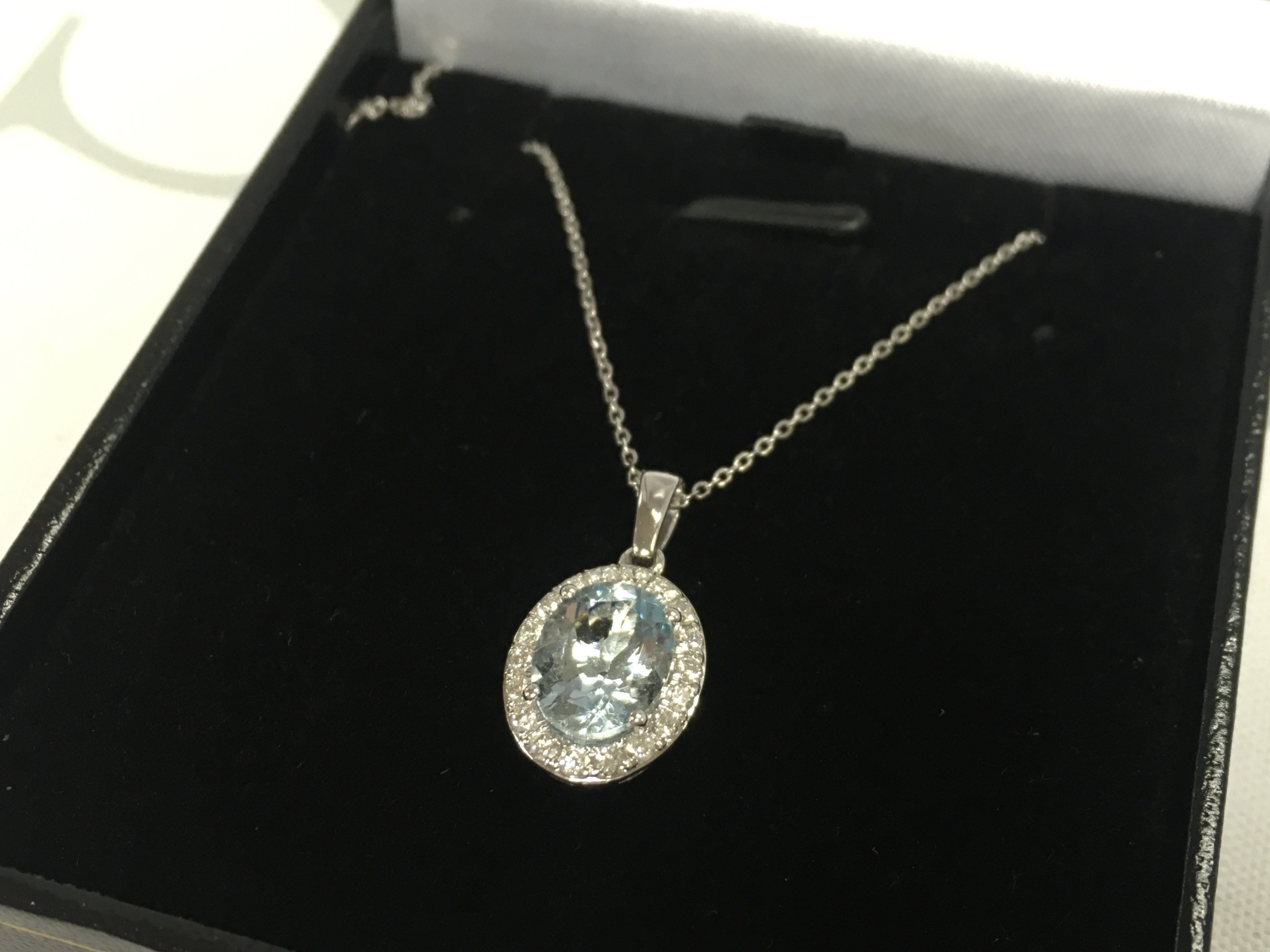 A 18ct white gold oval aquarmarine and RBC diamond cluster pendant on an 18ct white gold chain, boxed. Aquamarine 1.01ct , diamonds 0.32ct. 